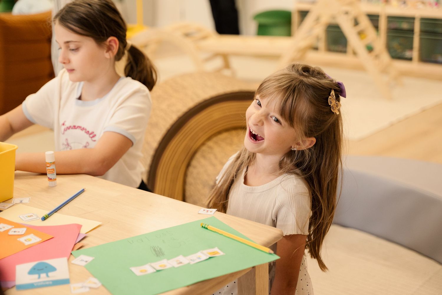 Students engaged in creative activities at a colorful learning table.