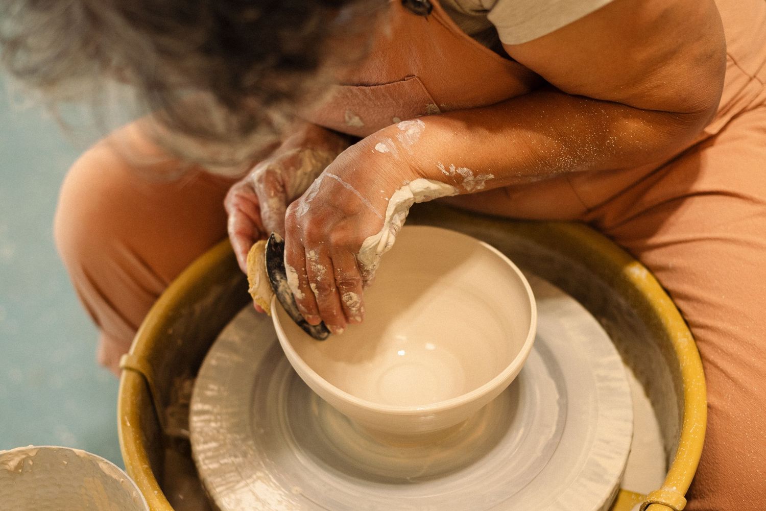 Close-up of hands working with clay on a pottery wheel, shaping a ceramic vessel.