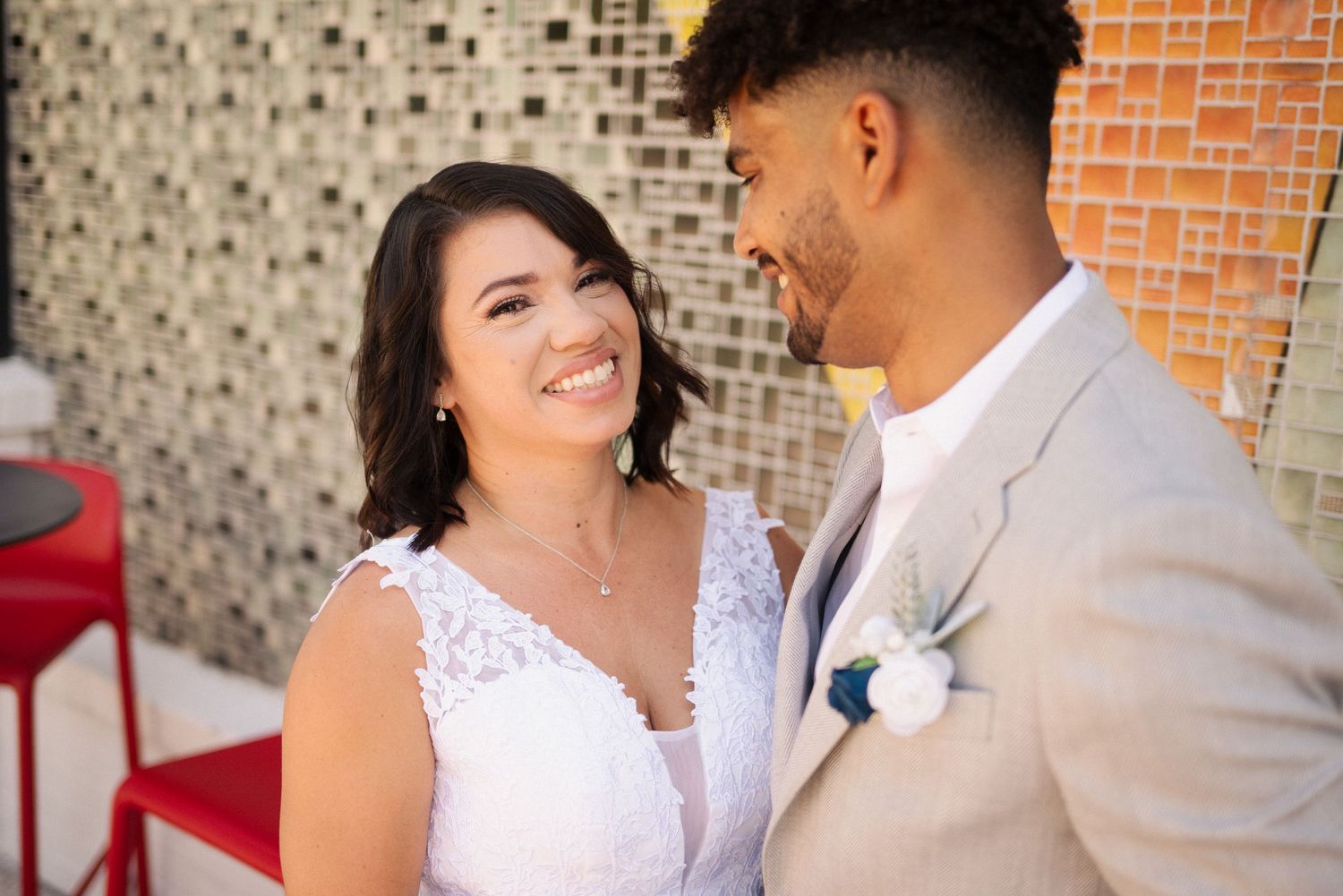 Wedding couple shares intimate moments against a brick wall background.