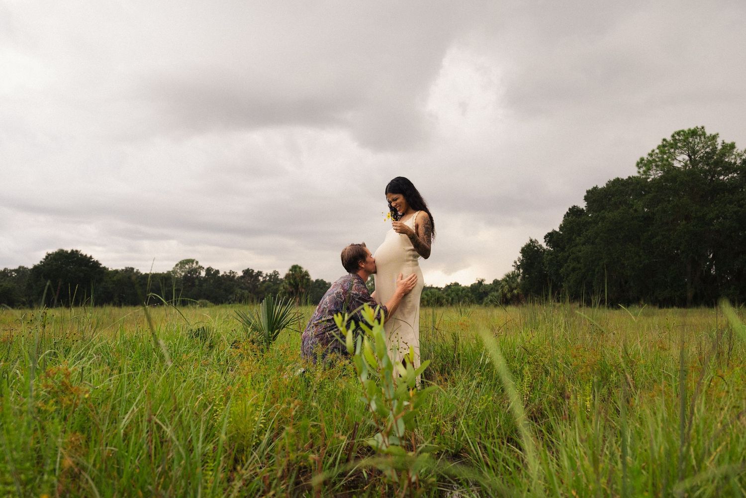 Two people walking through tall grass in a vast green field.