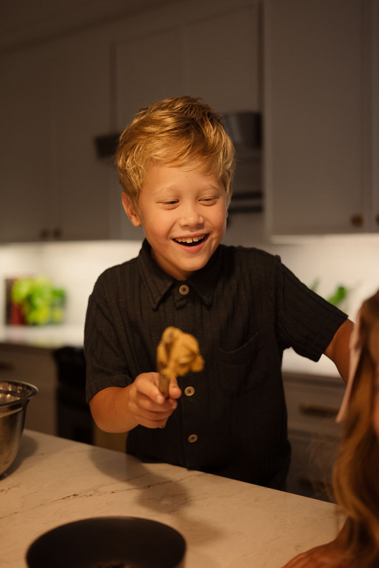 A child laughs with delight while sitting at a kitchen counter.