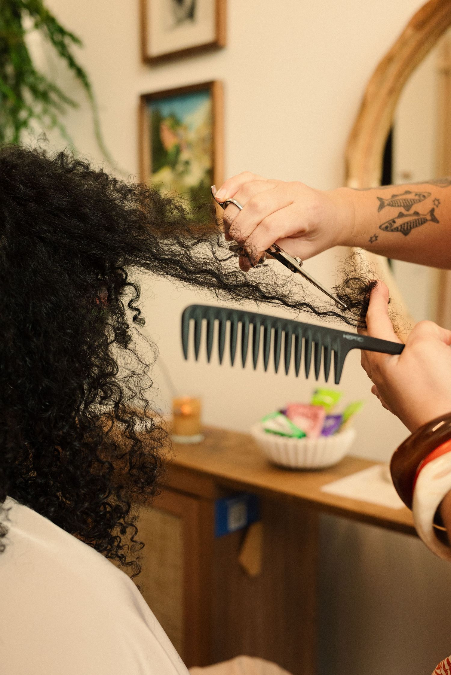 Professional hair styling tools being used to work on curly hair in a salon setting.
