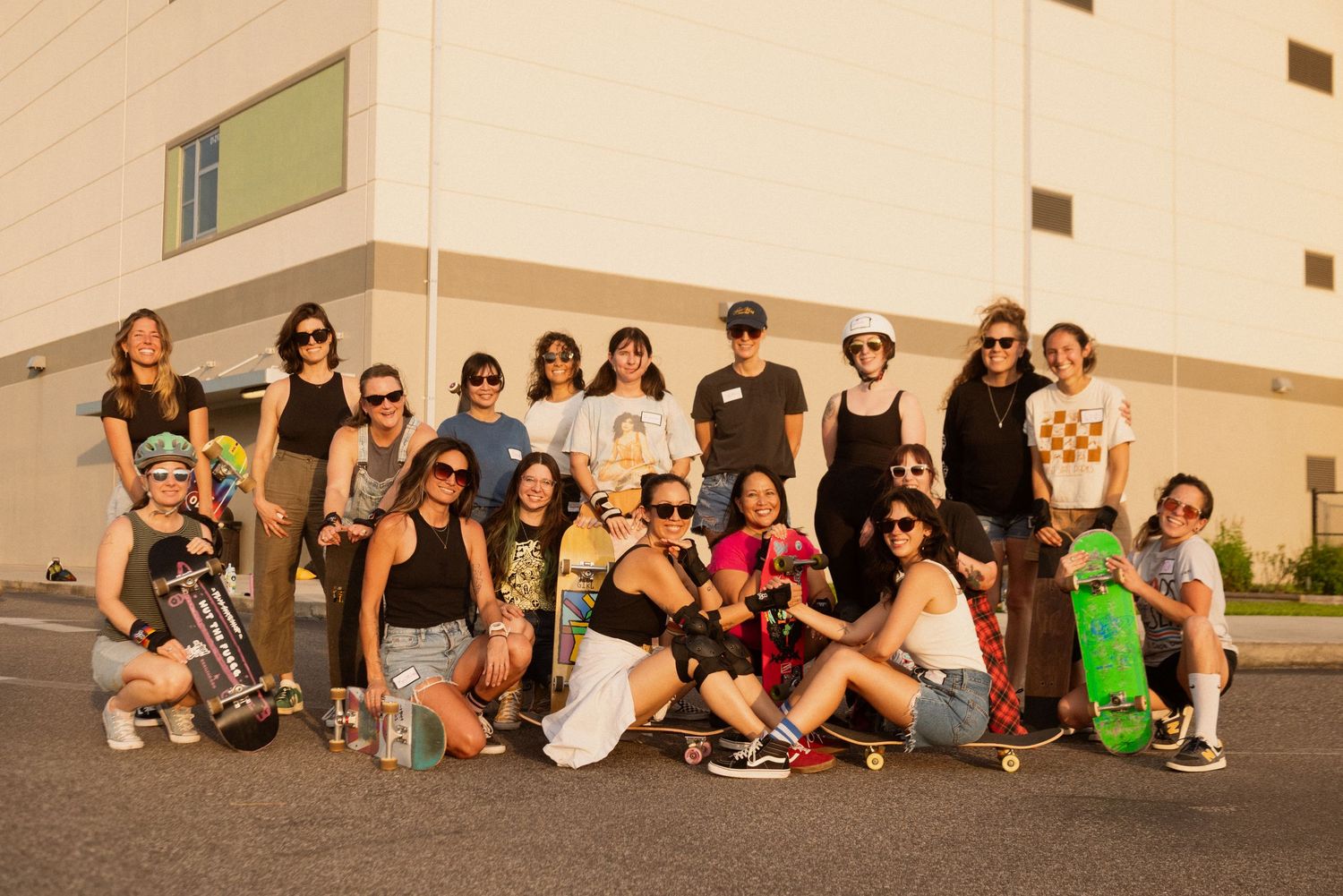 A large group of people sitting casually along an outdoor wall during a gathering.