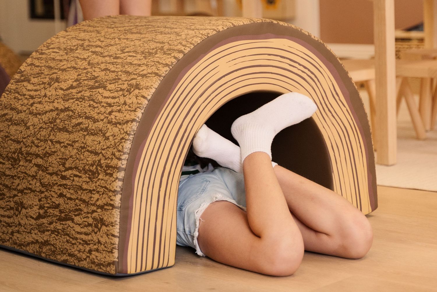 Curved wooden tunnel structure shown from multiple angles in an indoor setting.