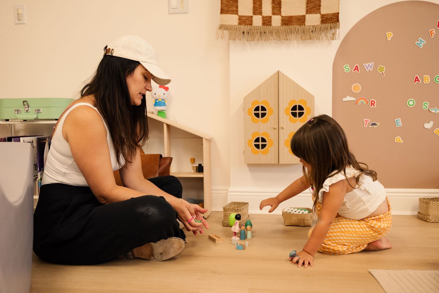 Children playing in a cozy playroom with decorated beige walls.