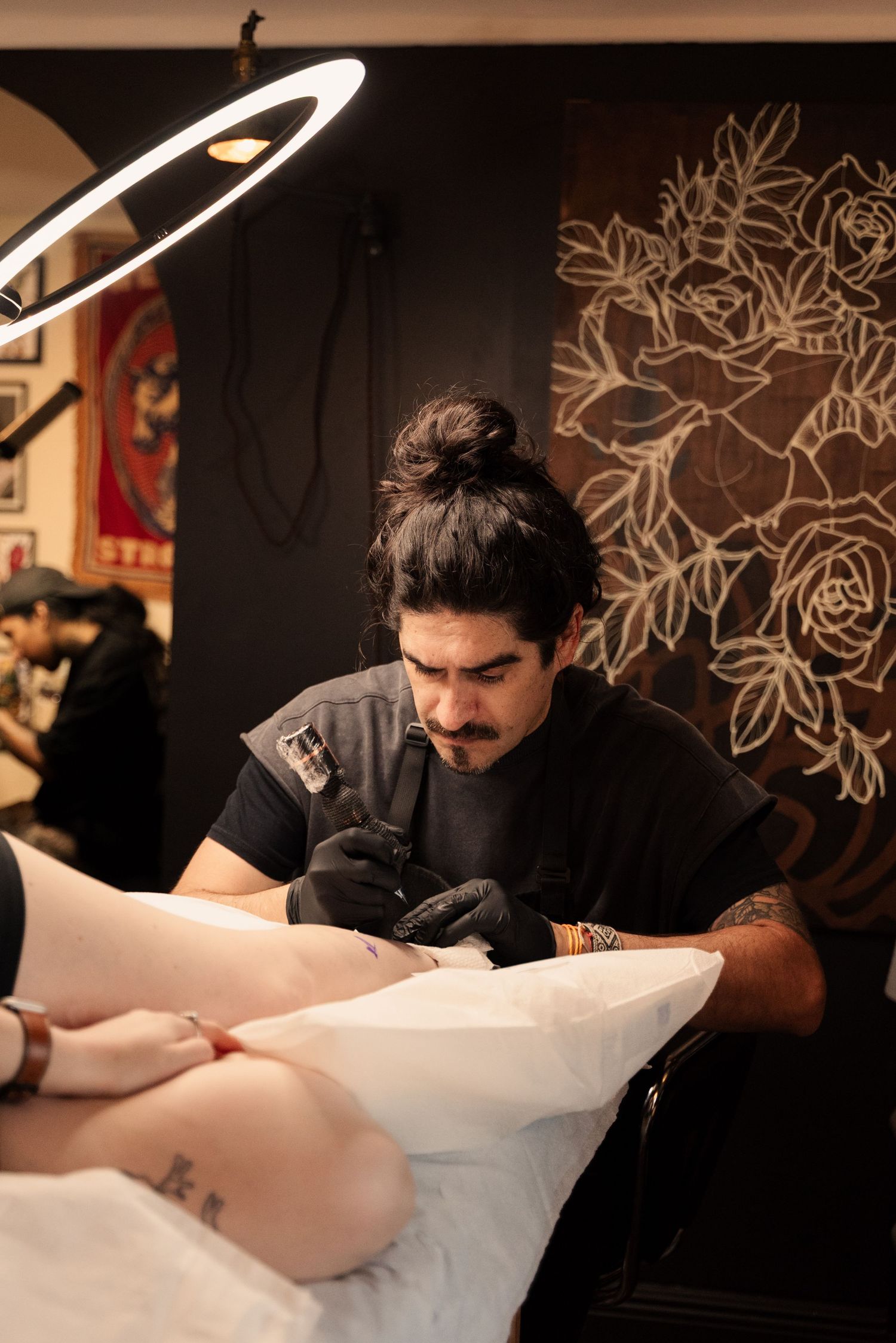 Tattoo artist carefully works on a detailed design in a professional studio setting.