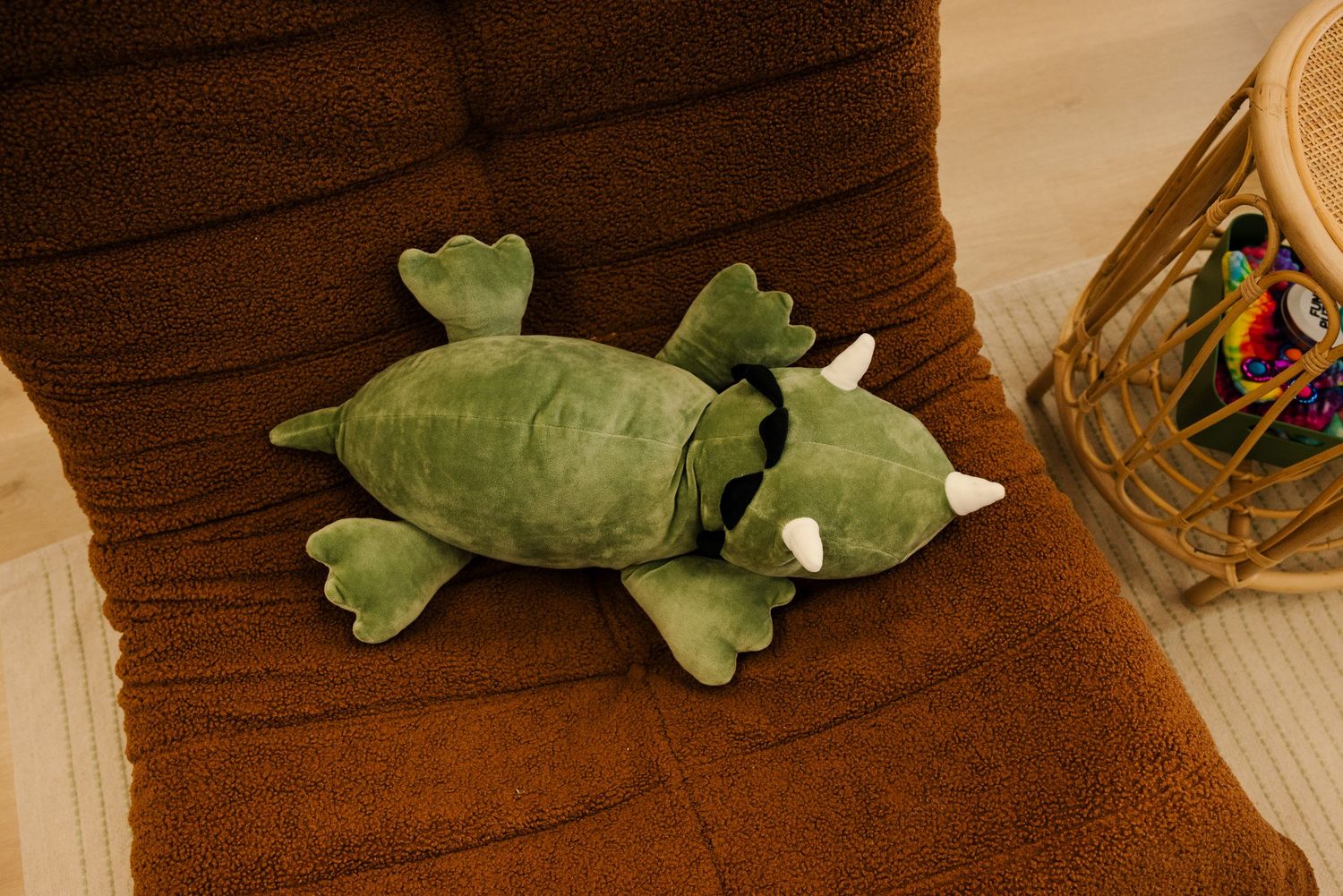 Plush green toys arranged on a dark wooden surface.