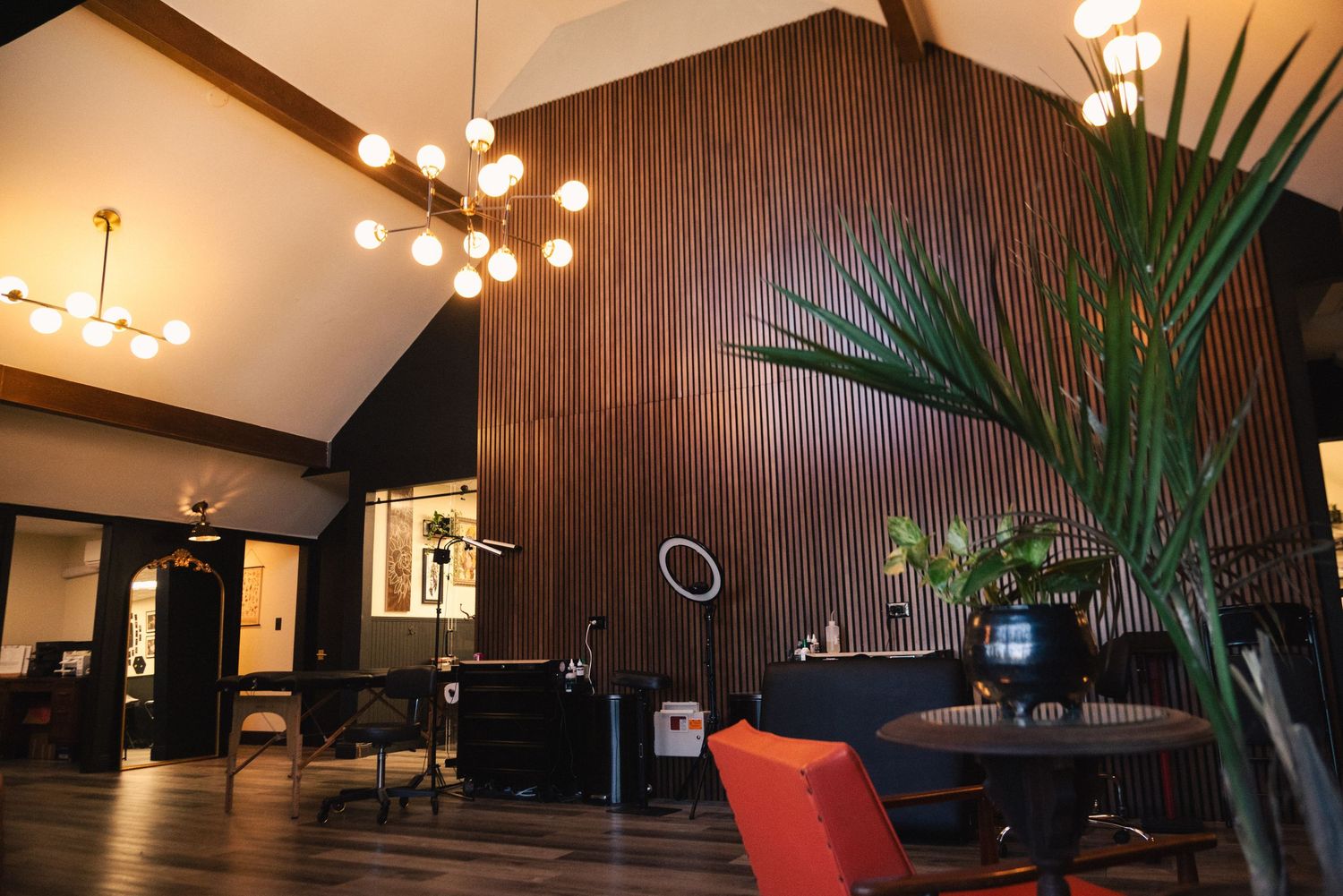Stylish lounge area with modern lighting fixtures and tropical plants against dark walls.