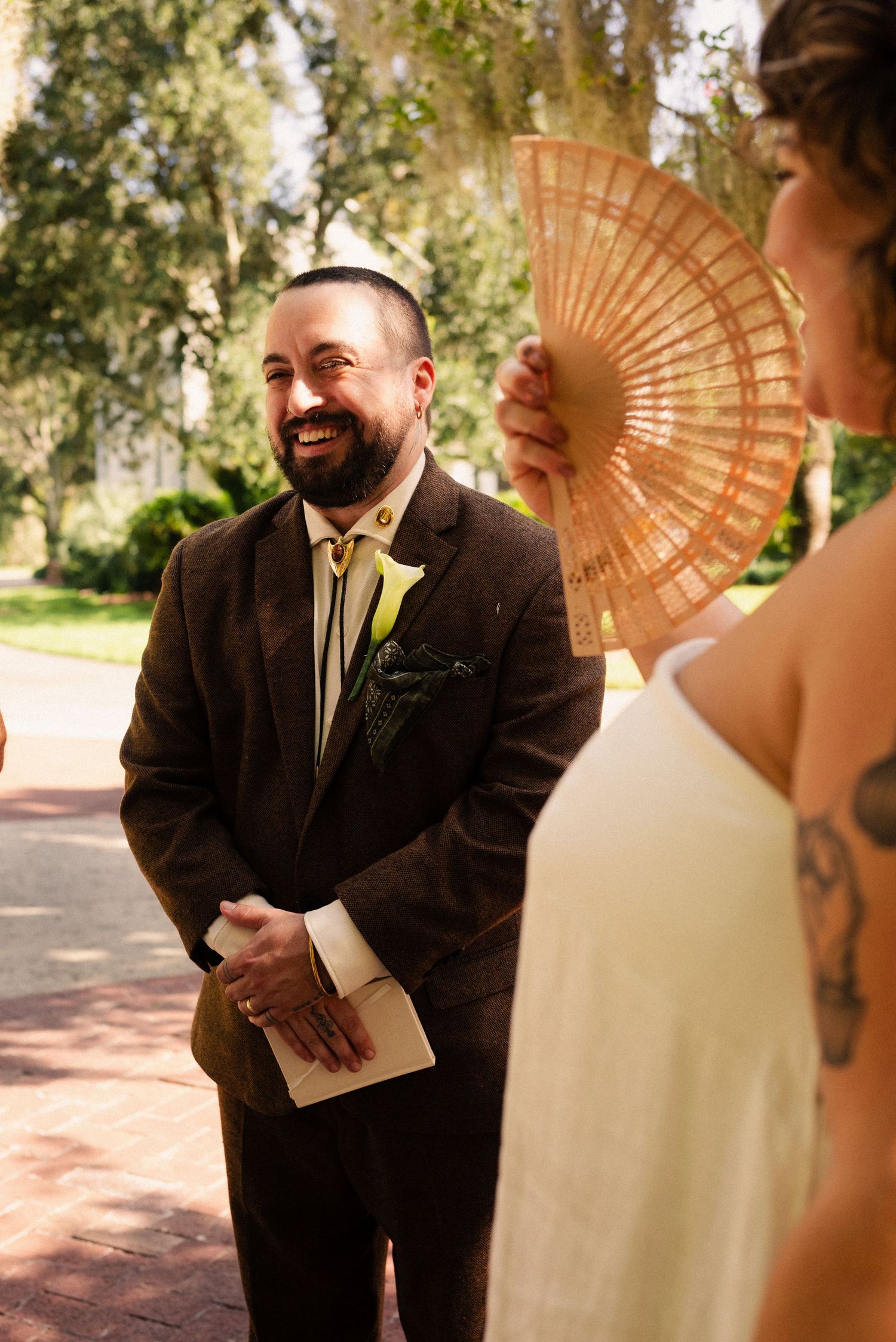 A couple shares an intimate moment during their wedding ceremony while holding a decorative fan.