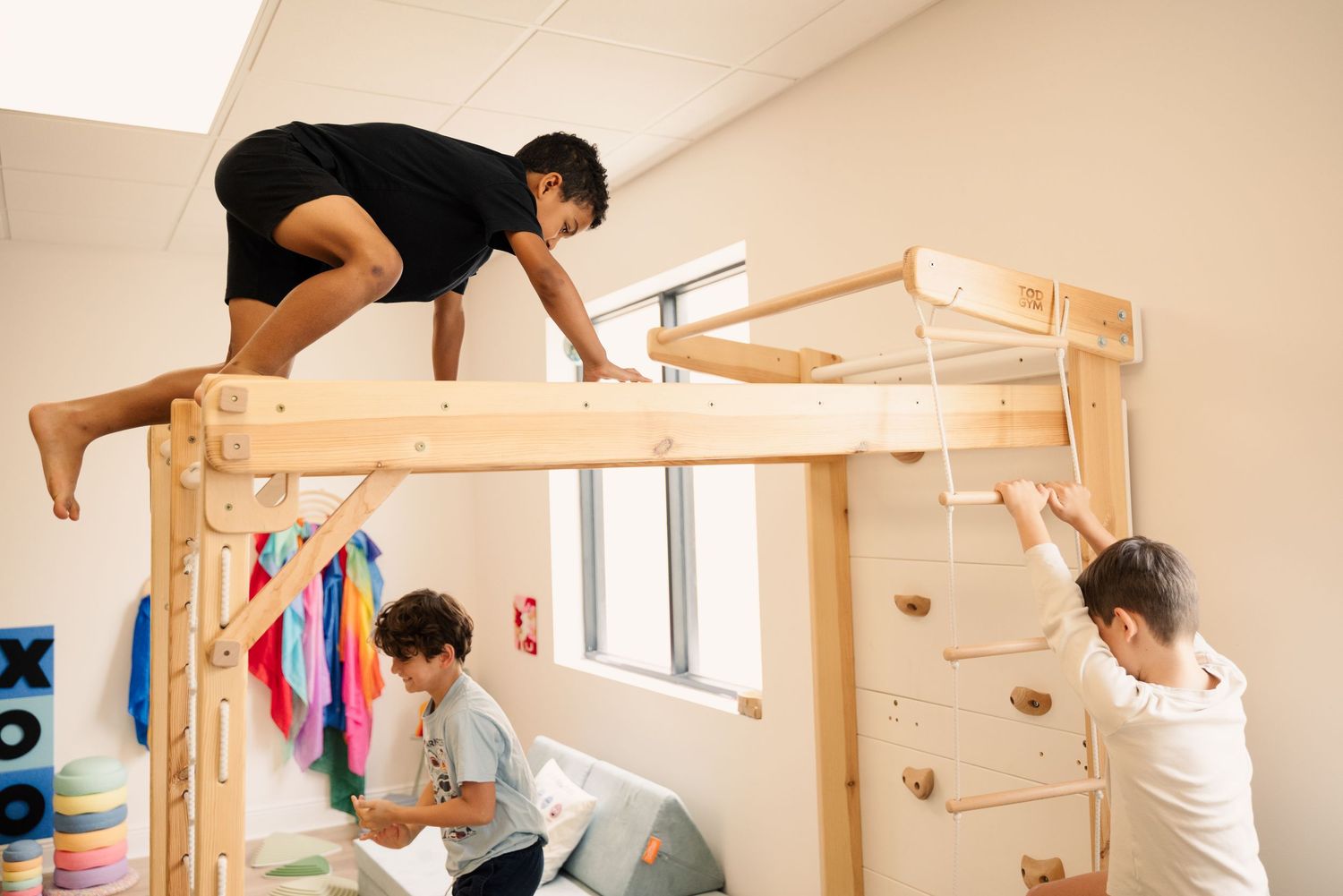 Indoor play area with wooden climbing equipment and natural lighting from windows.