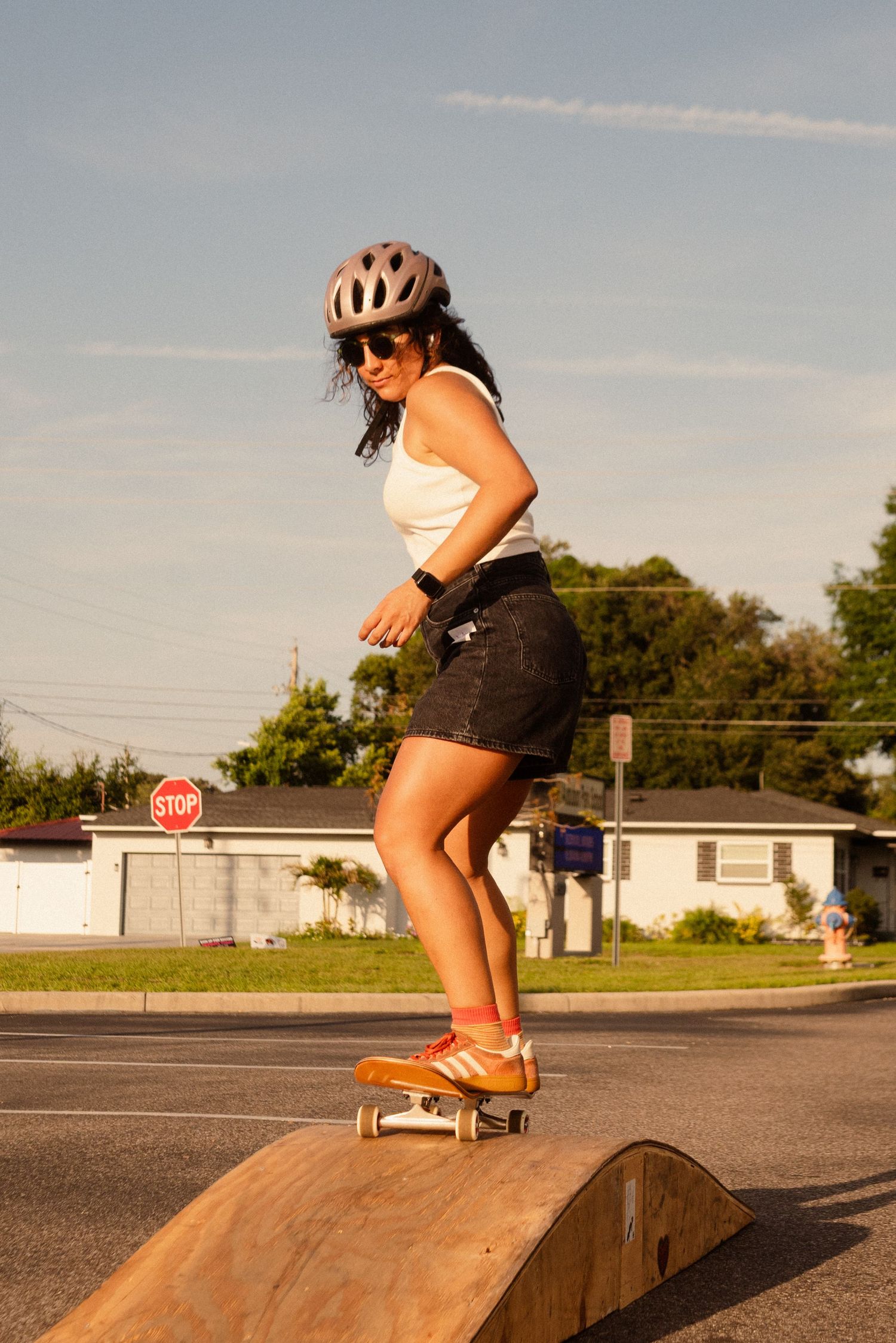 Skateboarding sequence showing tricks performed on a small ramp in a parking lot at sunset.