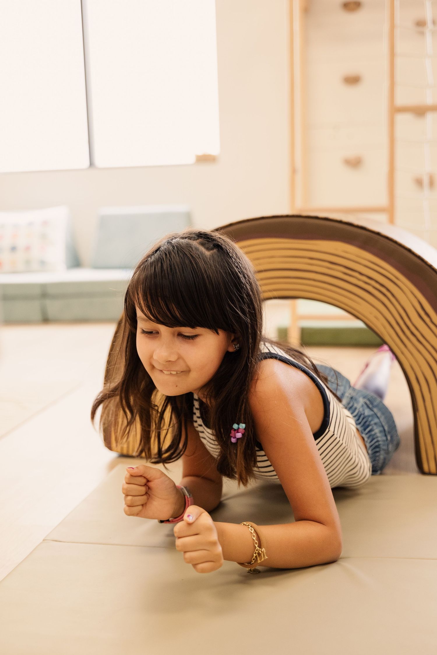 Child relaxing on cushioned surface with rainbow arch decor in background.
