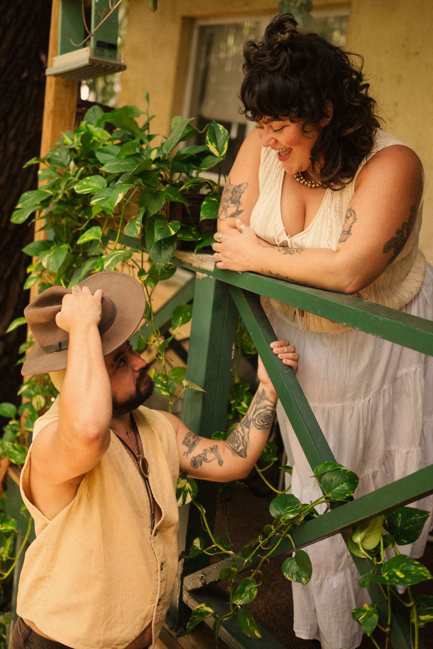 A romantic couple shares intimate moments on a porch with green vines and natural lighting.