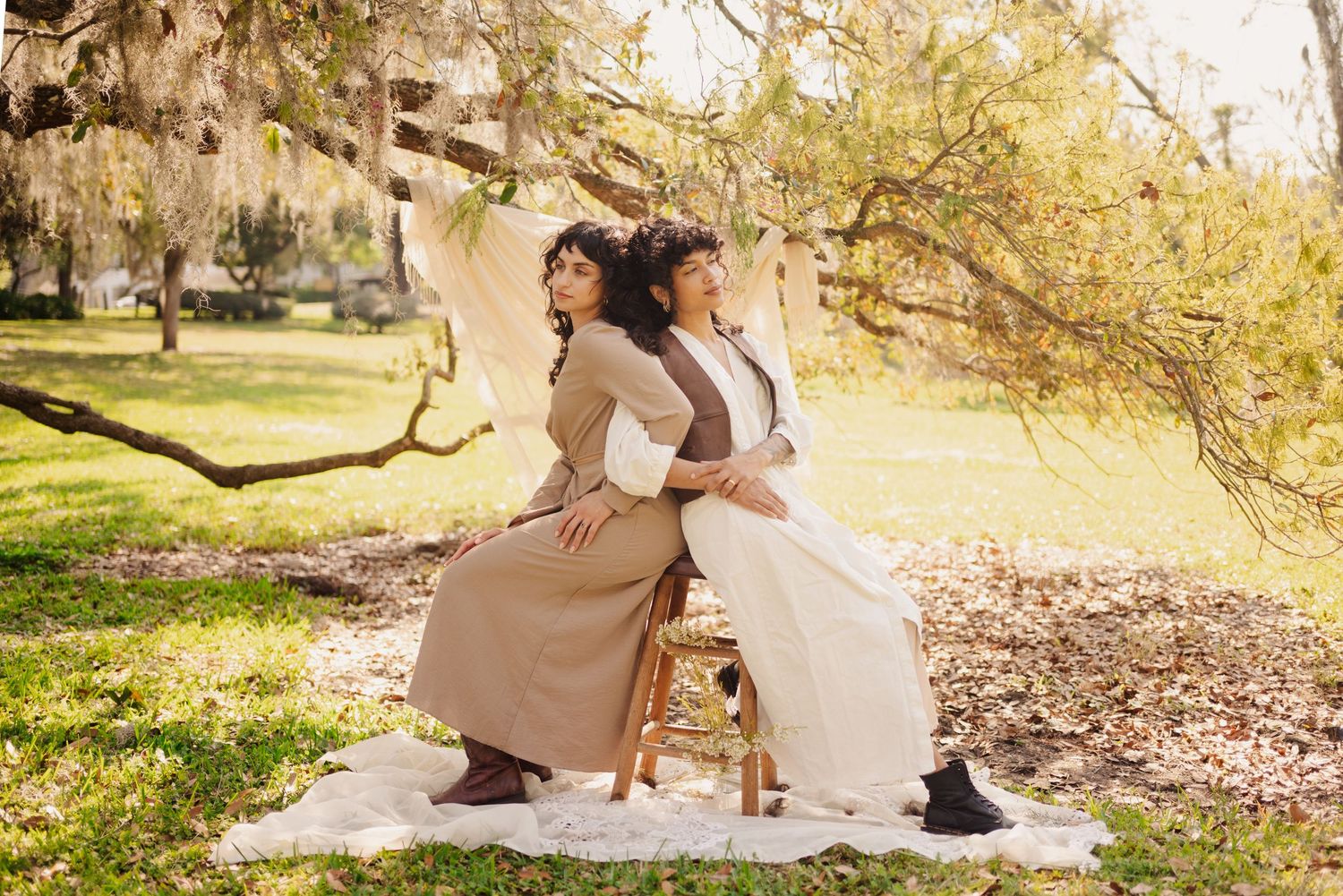 Elegant outdoor photography session with cream-colored fabric backdrop and natural lighting.