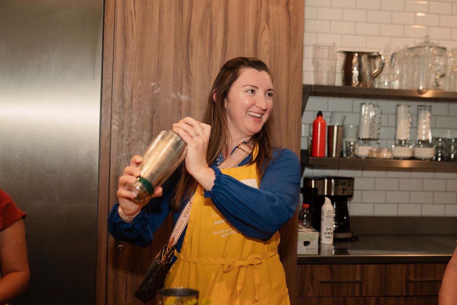Students learning mixology techniques in a modern kitchen with stainless steel appliances.