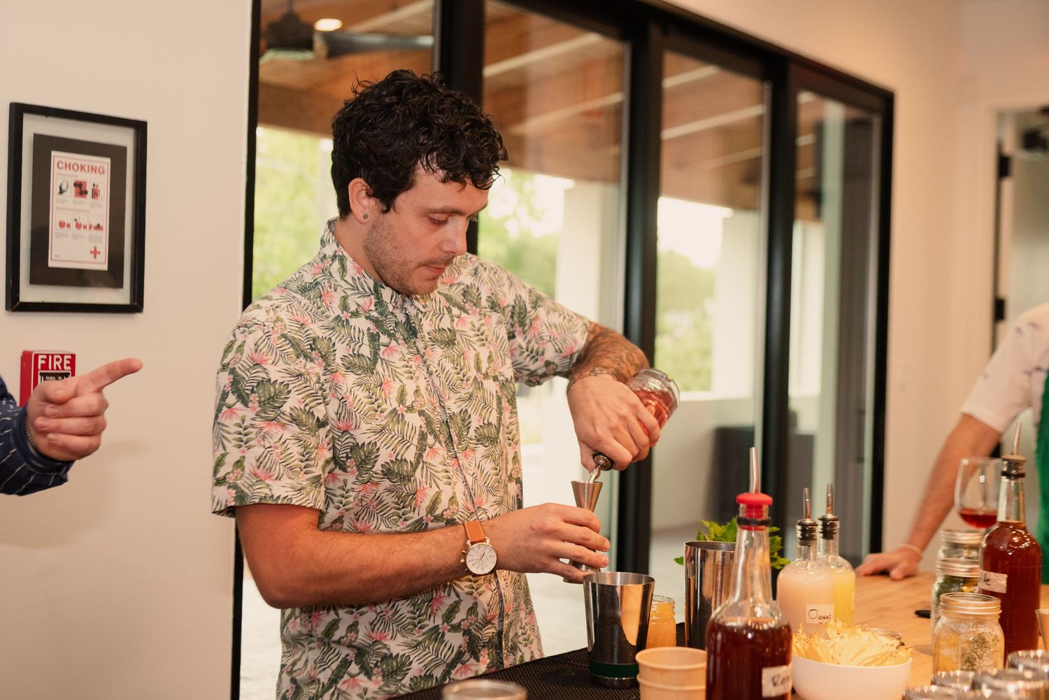A cocktail making class with participants in a modern kitchen setting mixing drinks and following instructions.