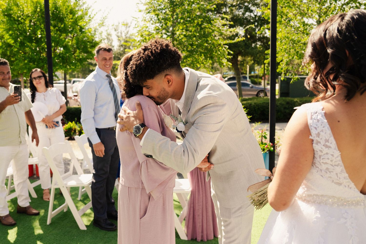 Wedding celebration on a green lawn with string lights and a colorful geometric greenhouse structure.