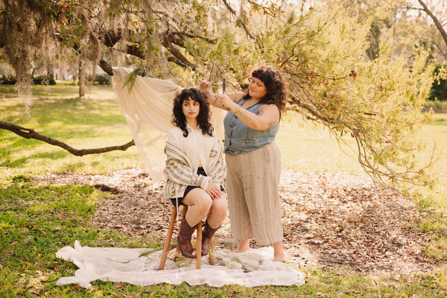 Outdoor picnic scene with people relaxing on a blanket under trees in warm sunlight.