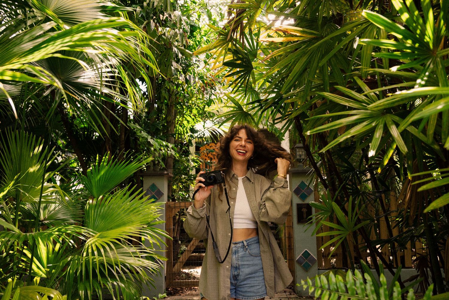 Tropical plants and palm fronds create a lush garden atmosphere.