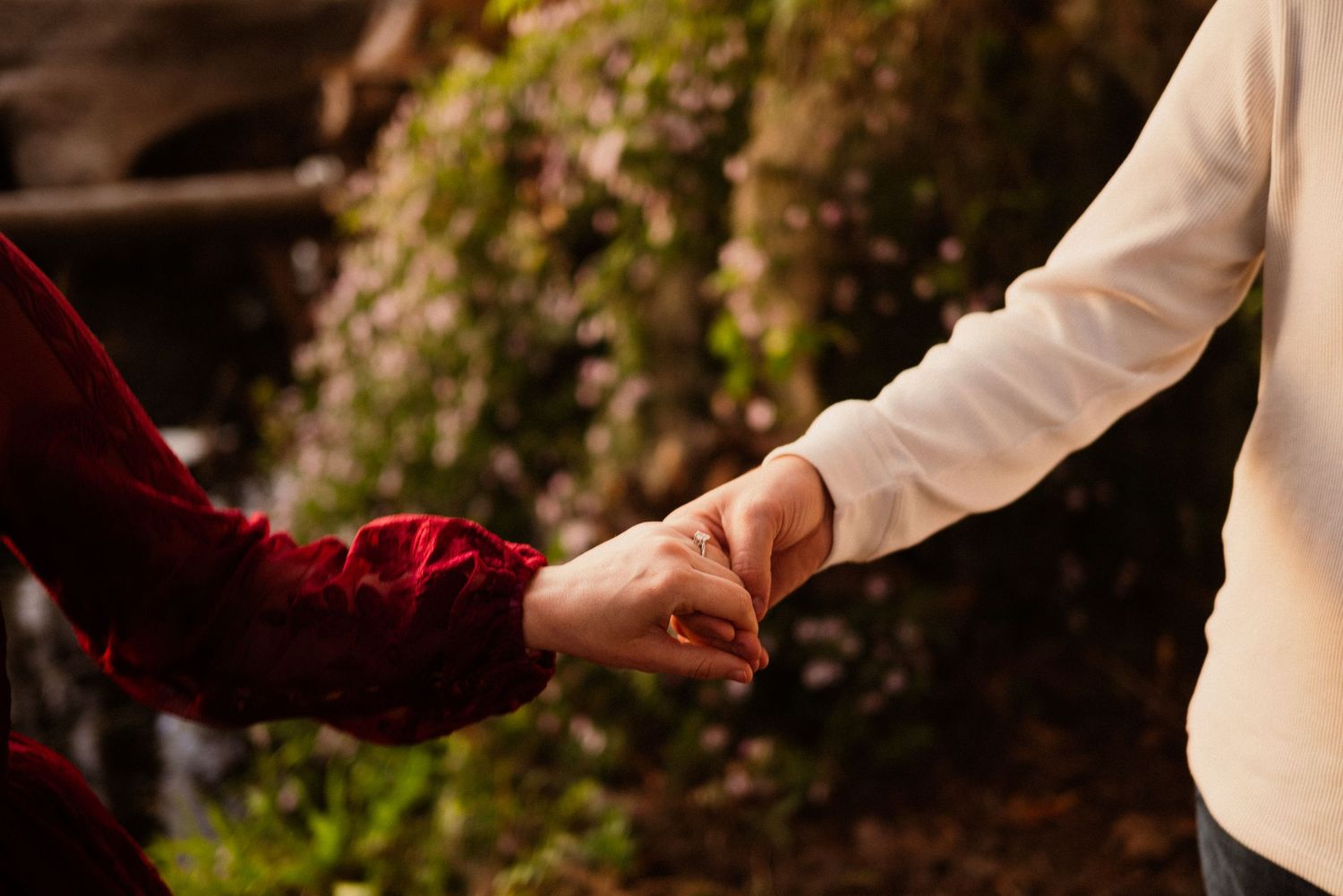 Couple in burgundy and white share tender moments during an outdoor sunset session.