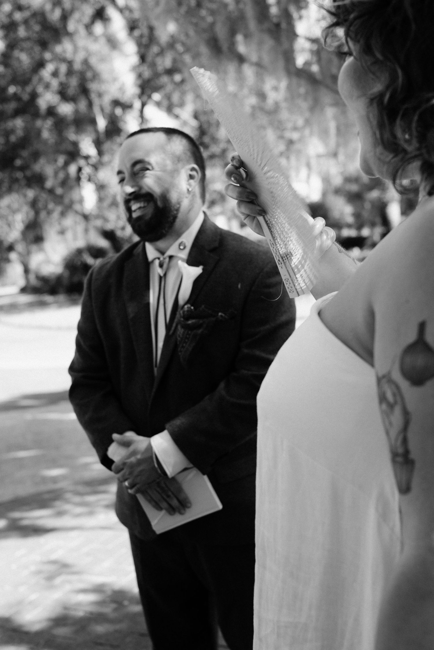 Black and white photo of wedding ceremony participants sharing emotional moment outdoors.