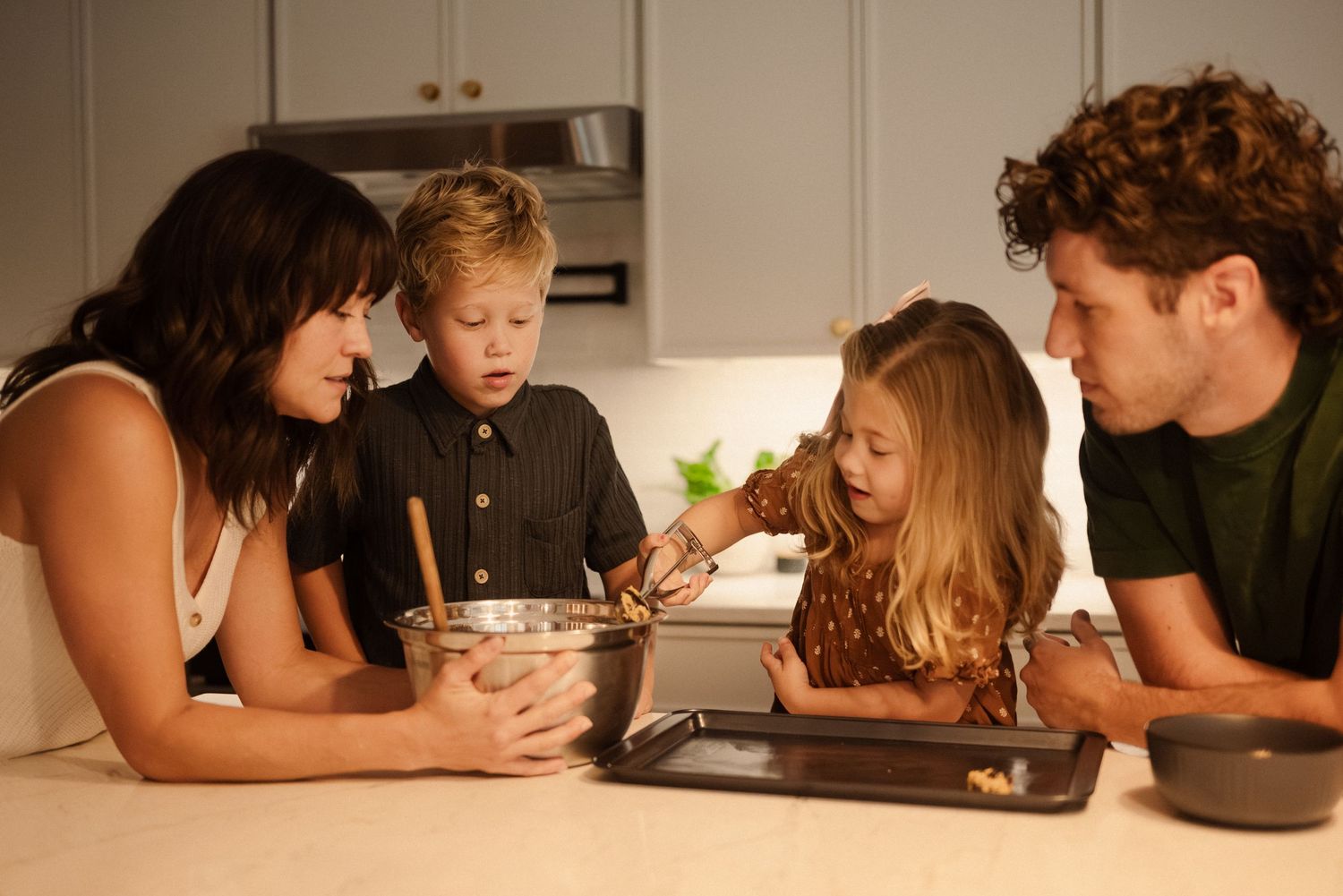 Family gathered around kitchen counter enjoying baking time together.