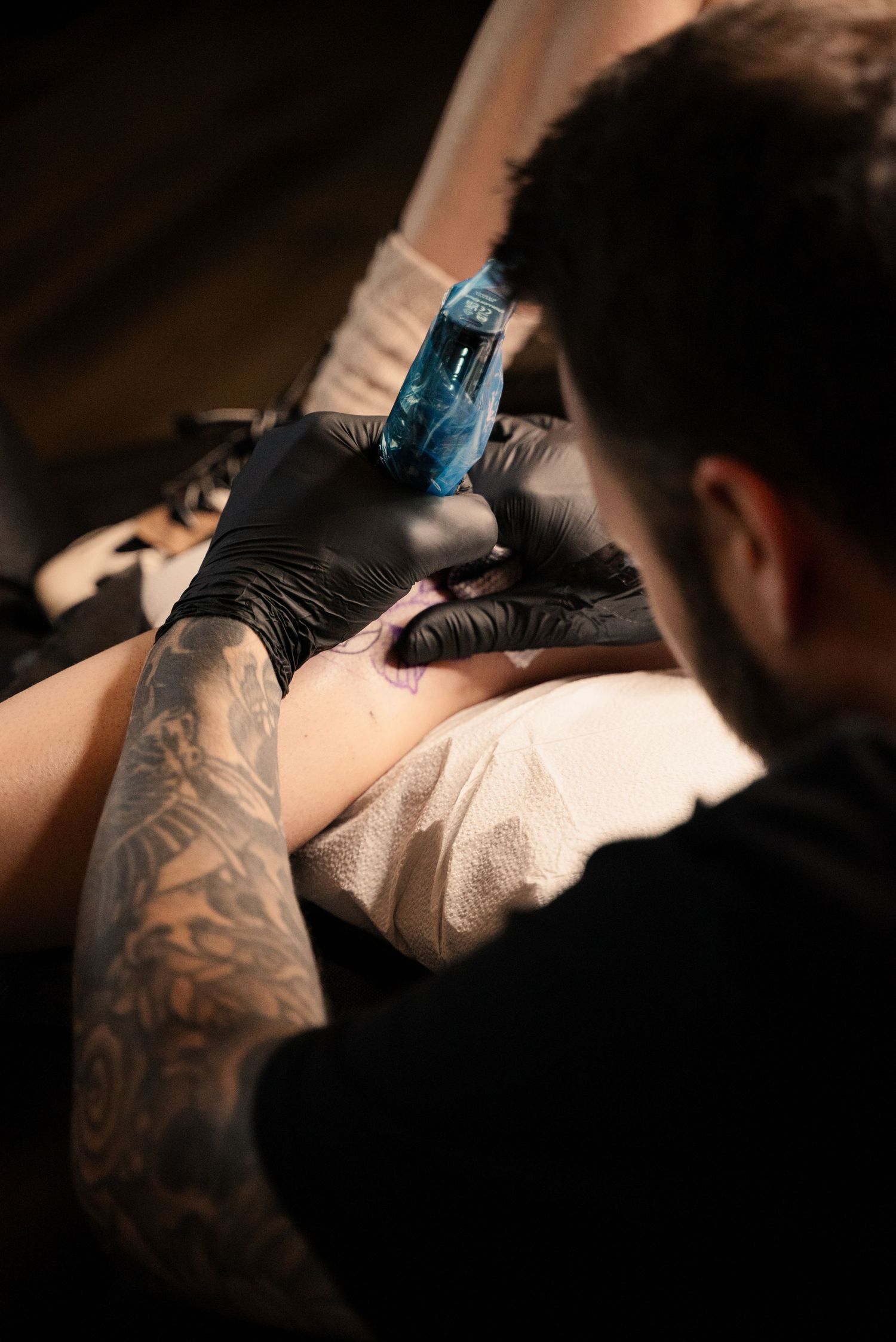 Close-up shot of tattooing process in dramatic lighting.