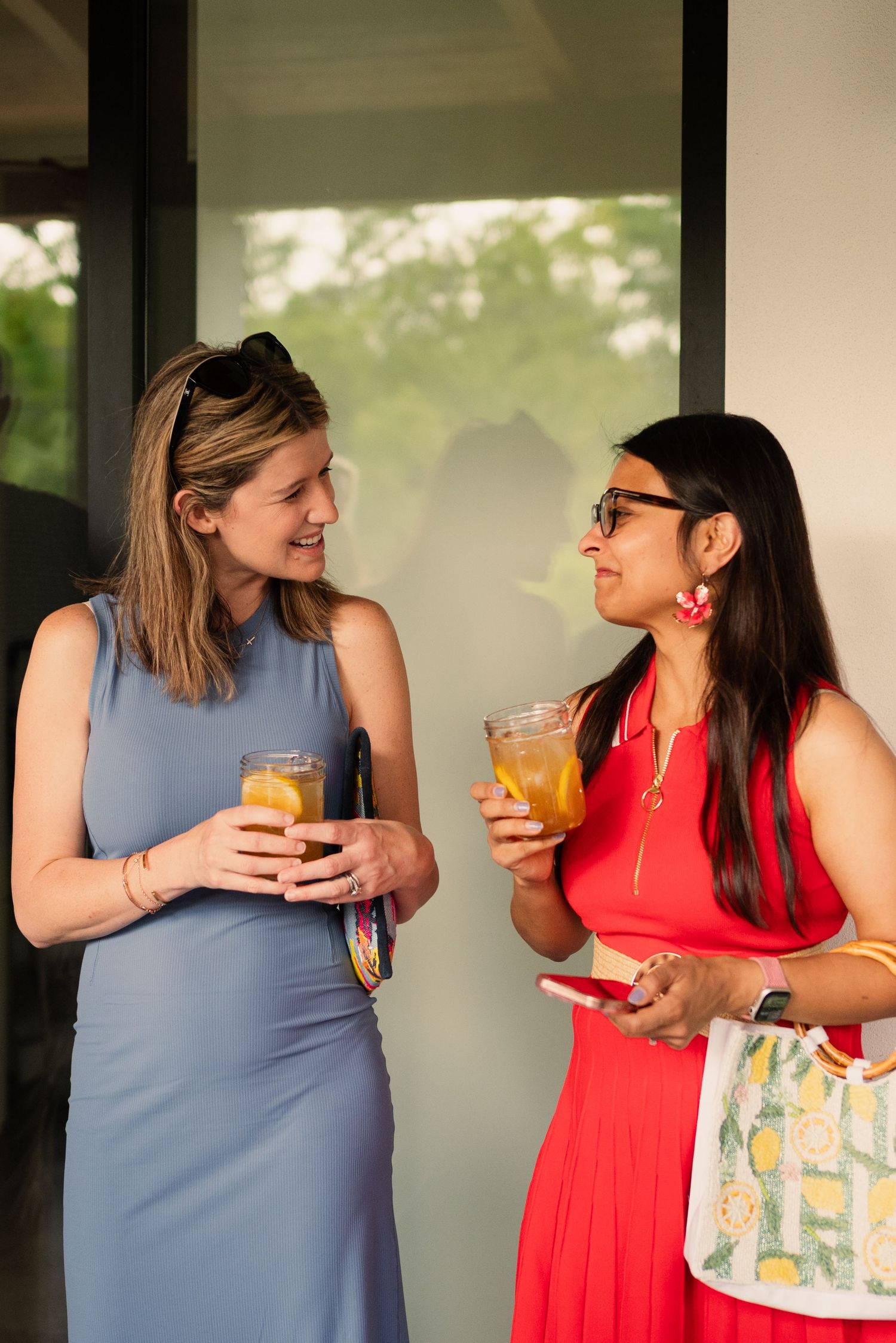 Two people enjoying drinks and conversation on a covered patio.