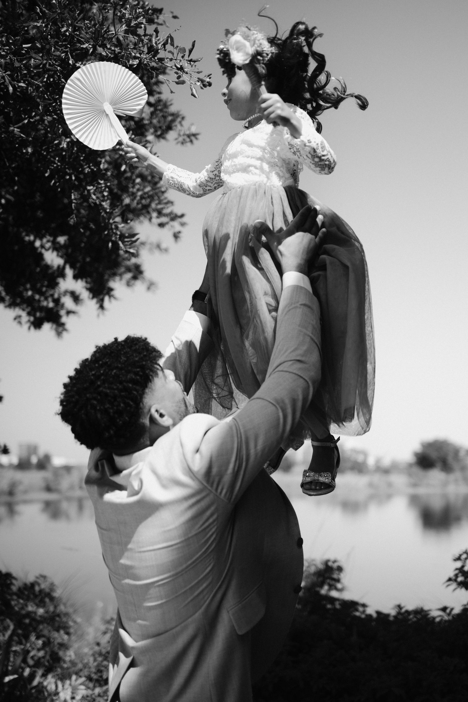 Black and white silhouettes of a couple dancing with paper fans outdoors.