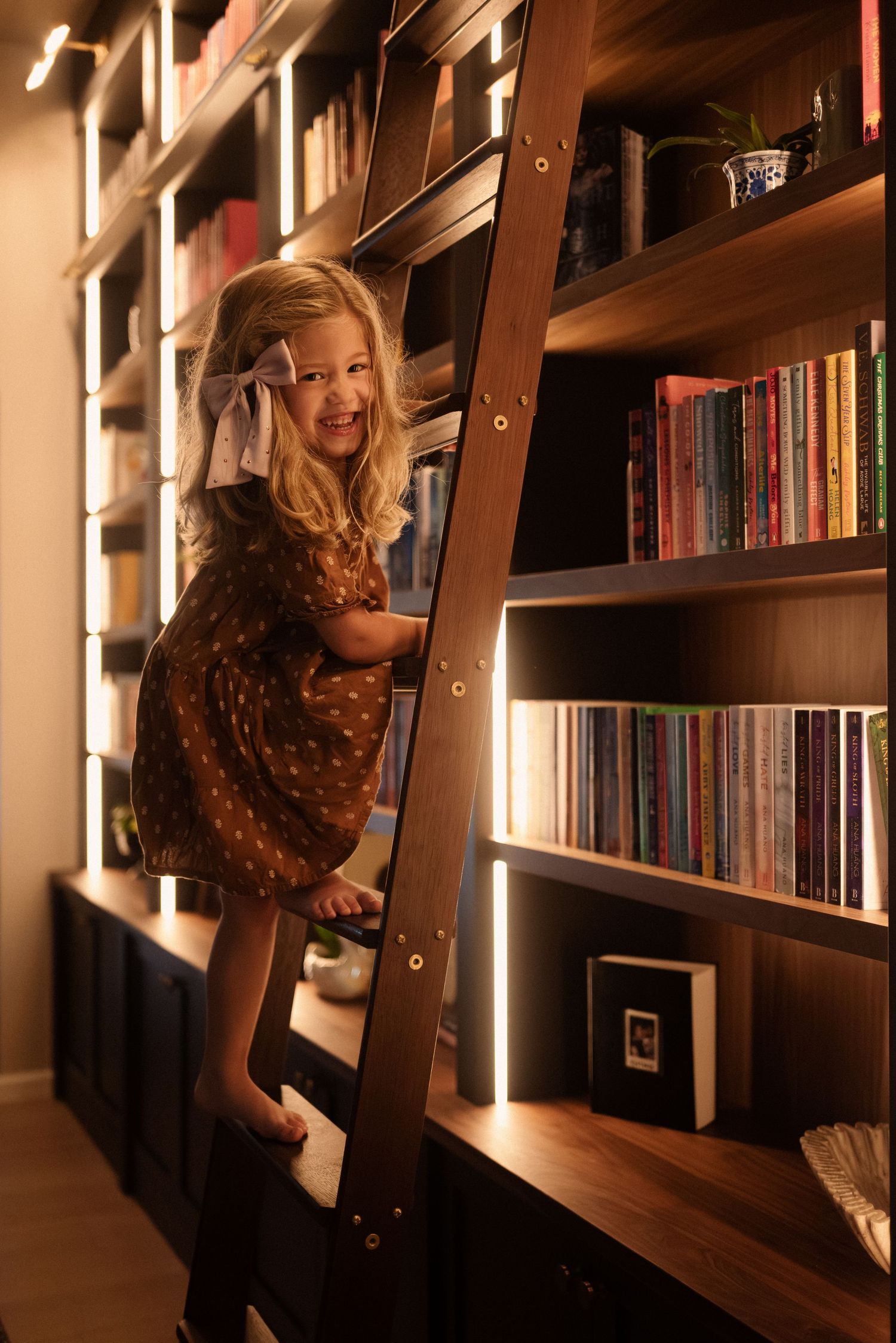 A library interior with wooden shelves and built-in lighting creates a cozy reading atmosphere.