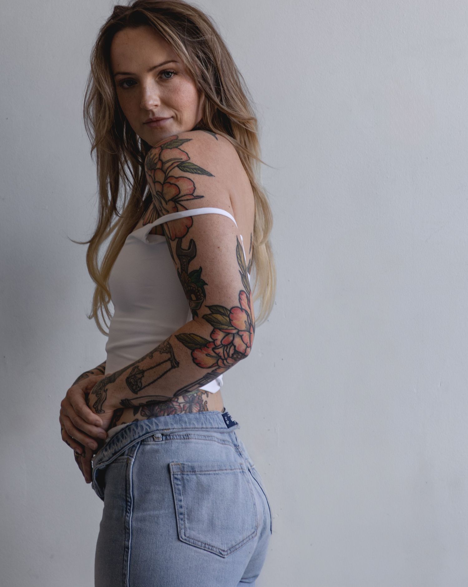 Person in denim and white top poses against neutral background.