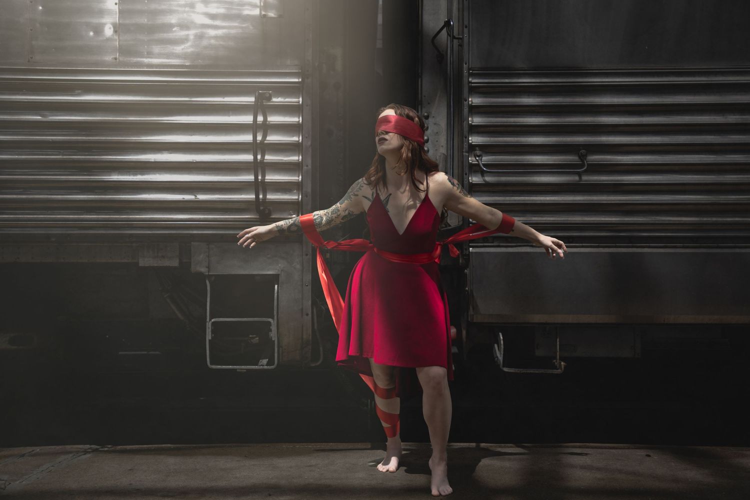 Dancer in red dress performs graceful movements in sequence against dark background with window blinds.