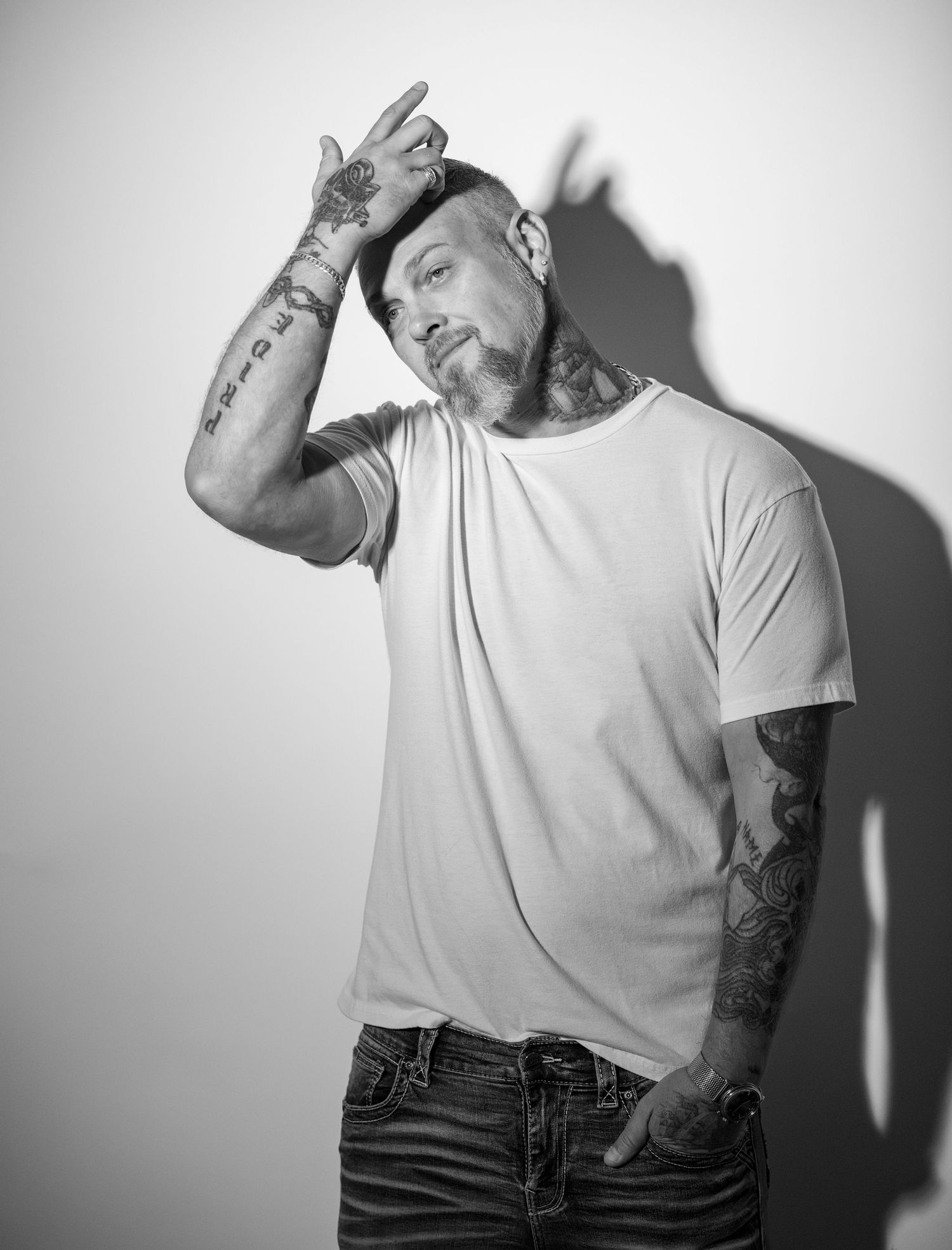 Black and white portrait series showing tattooed arms in casual white t-shirt.