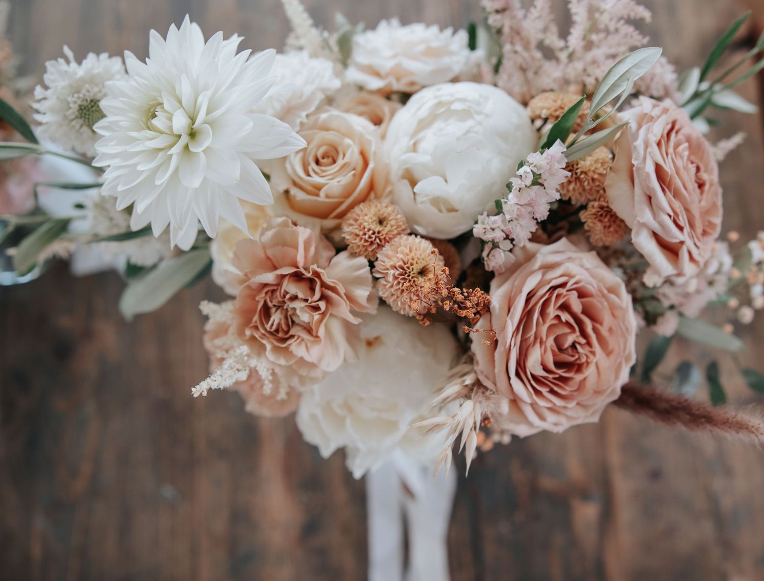 Romantic wedding bouquet with blush roses and white flowers in soft vintage tones.