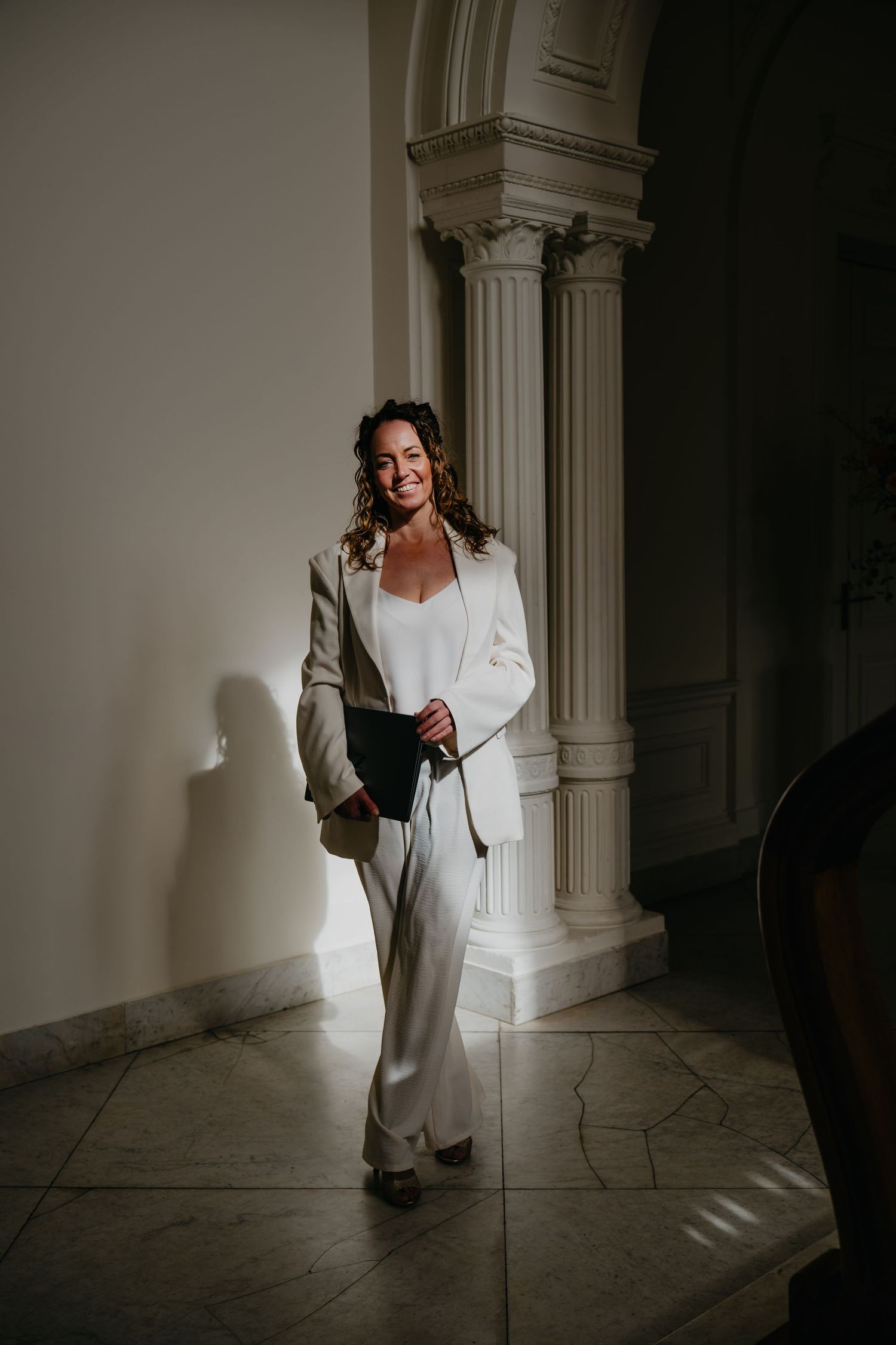 A series of moody photos shows someone in a white dress walking through a dark stone hallway with dramatic lighting.
