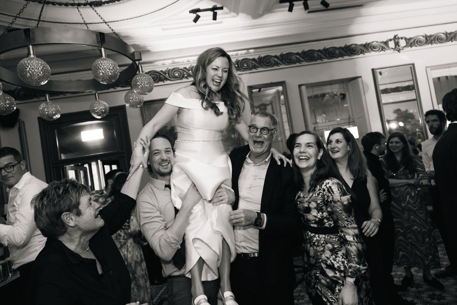 A group of people enjoying a lively social gathering in a dimly lit venue with candid black and white photography.