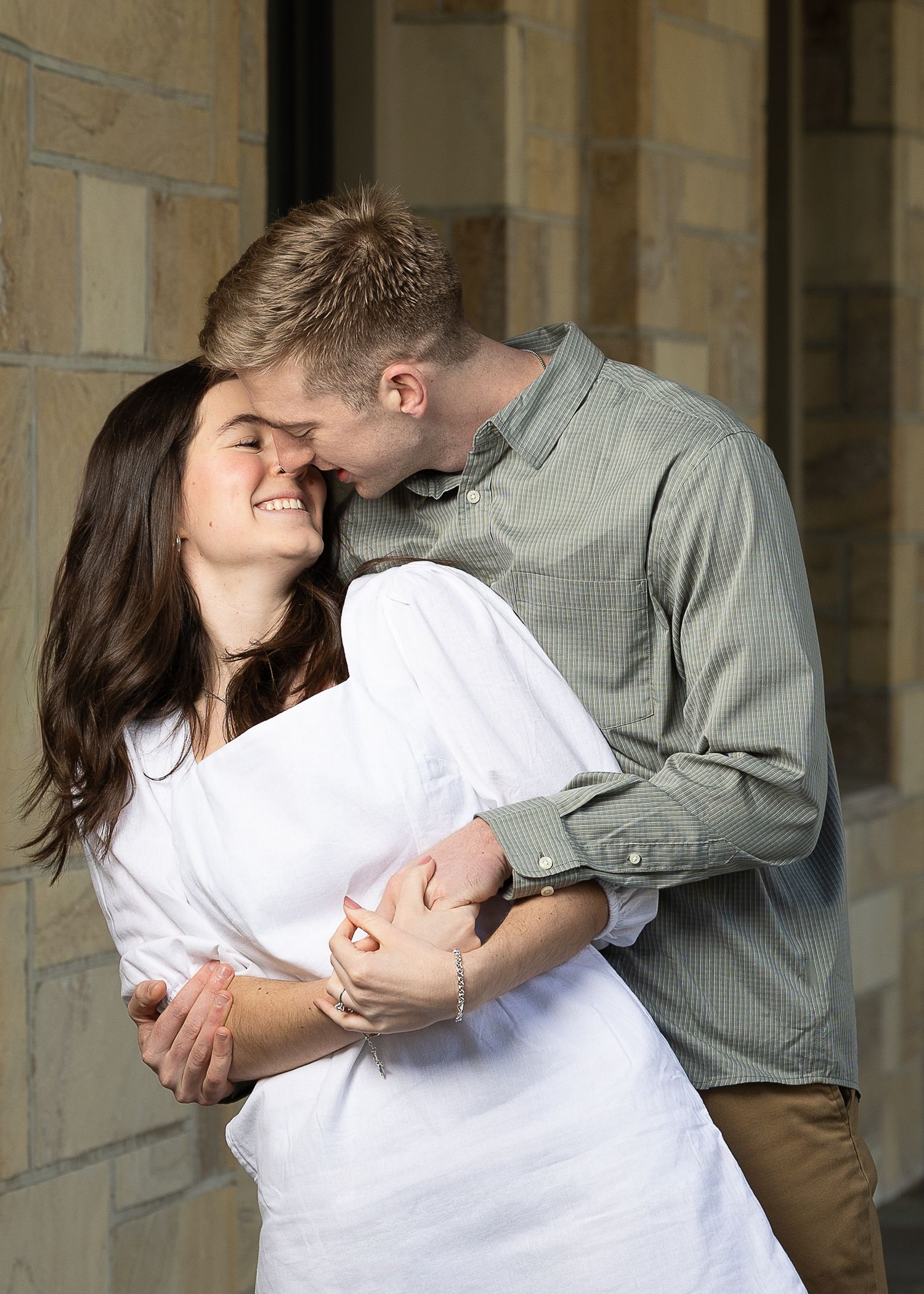 A newly engaged couple laughing together during a golden hour engagement photography session.