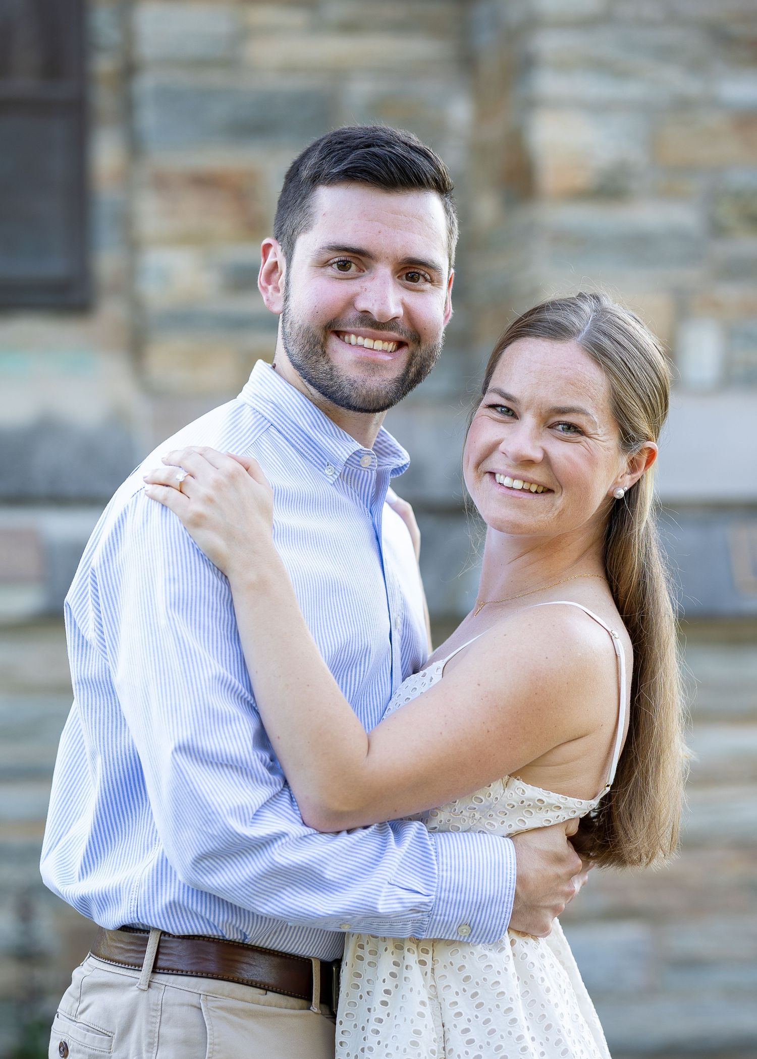 A newly engaged couple laughing together during a golden hour engagement photography session.