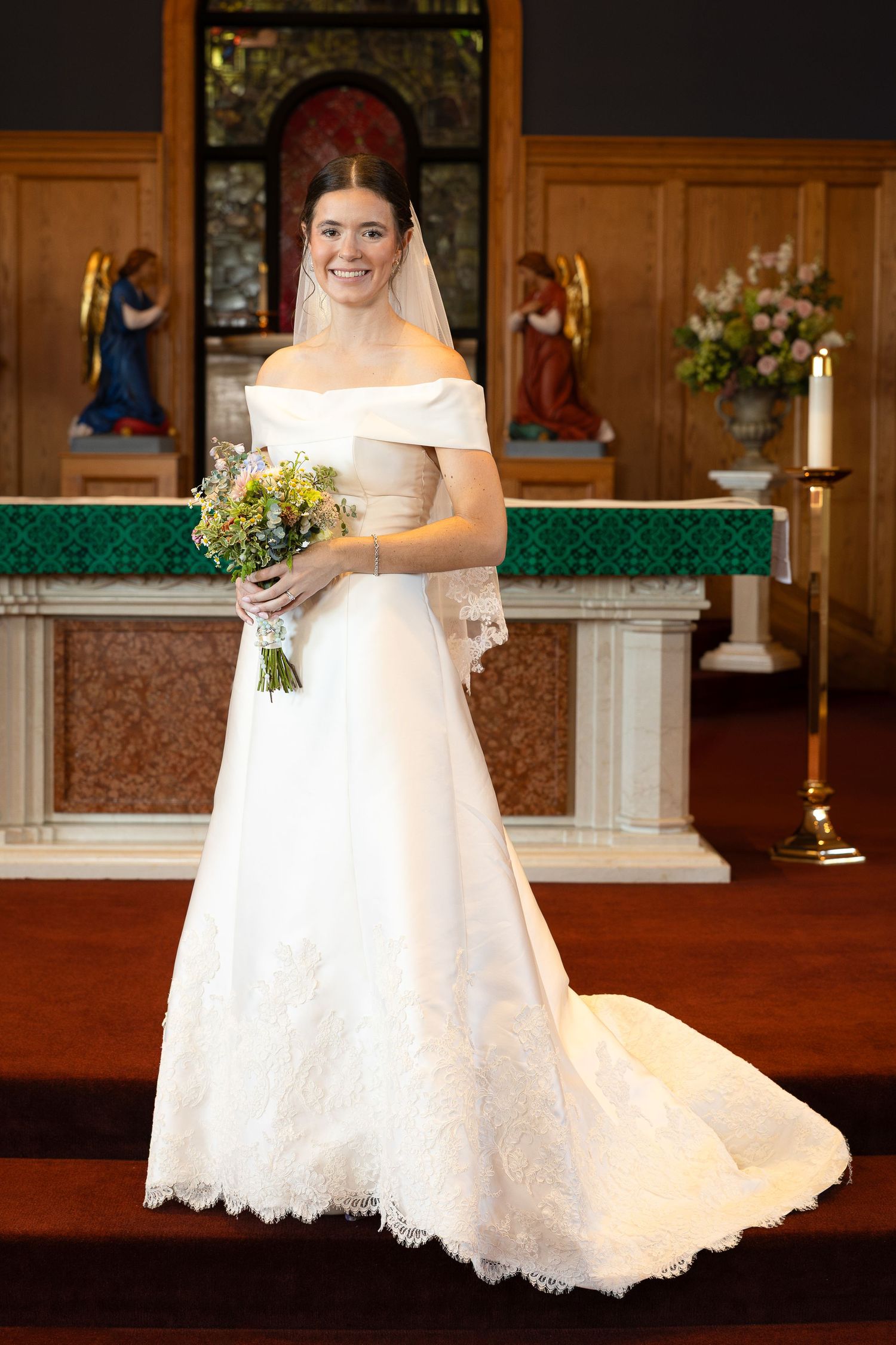 A beautiful bride standing and smiling after the Sacrament of Holy Matrimony at a Catholic church.