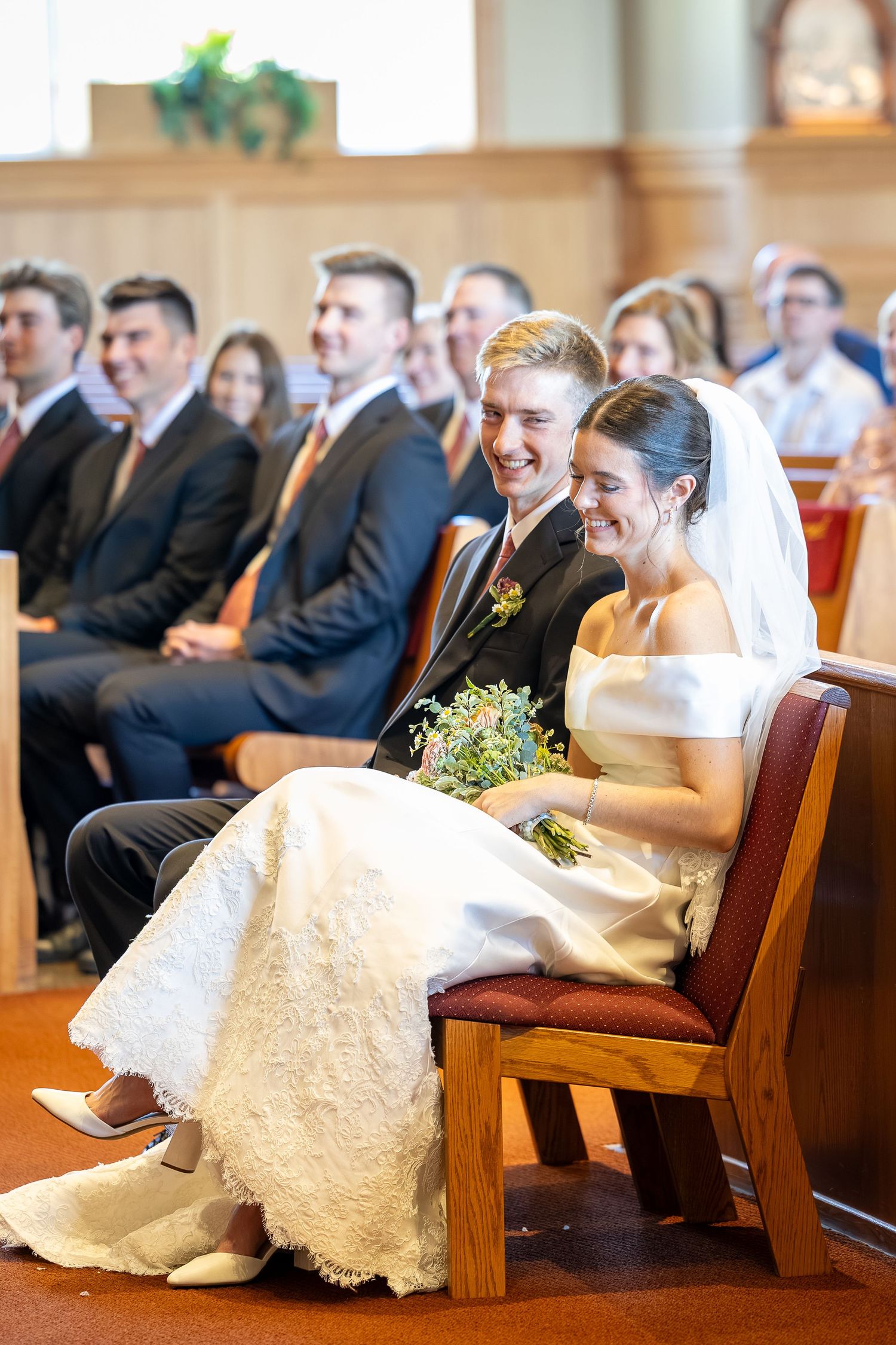 Bride and groom sitting before the altar during the Sacrament of Holy Matrimony at a Catholic church.