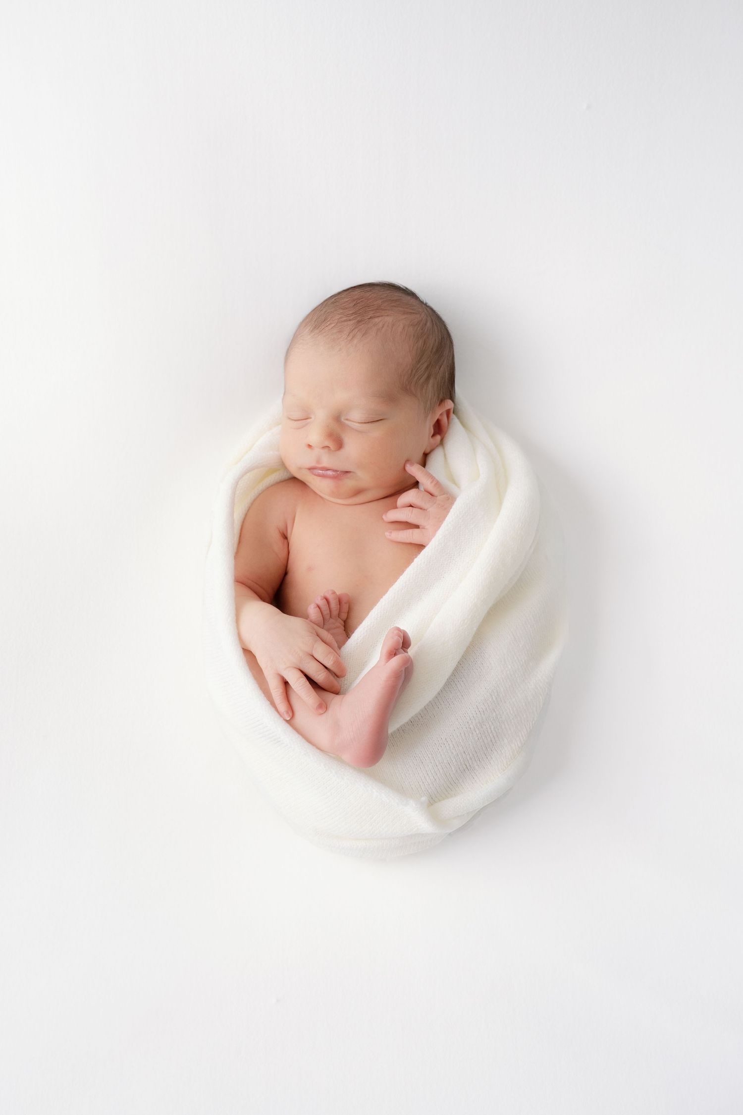 Newborn baby photographed in white fabric at Rockford Michigan photography studio