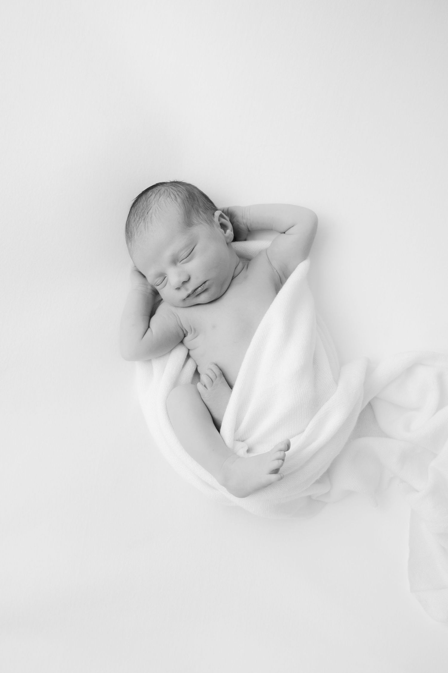 Newborn baby photographed in white fabric at Rockford Michigan photography studio