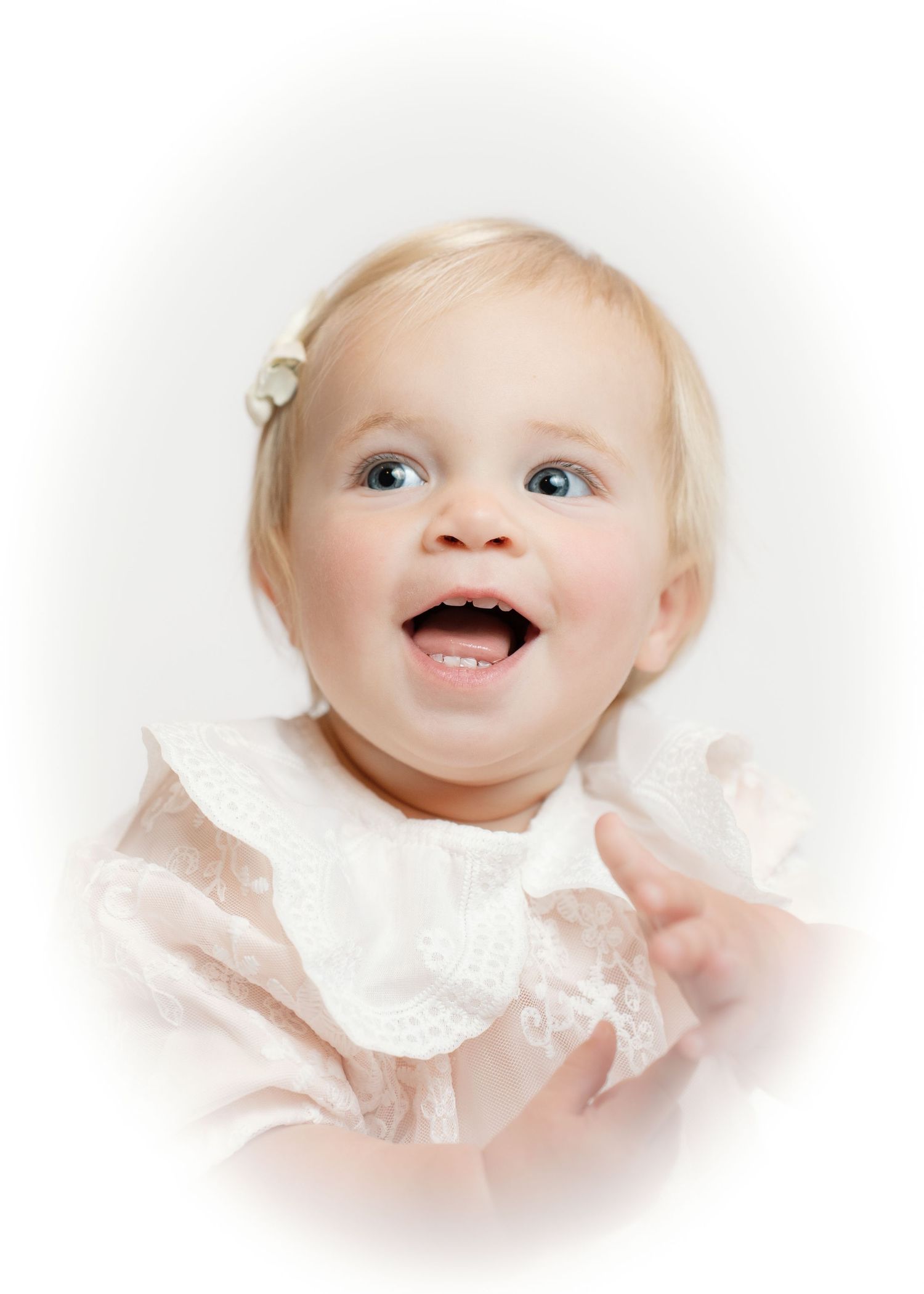 Laughing blonde baby girl in pink lace dress with soft white vignette border.