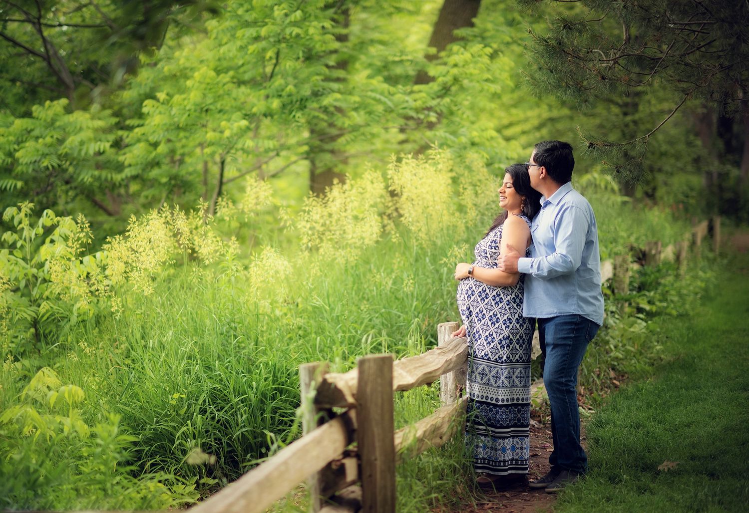 Couple standing together on wooded path with lush green forest background.