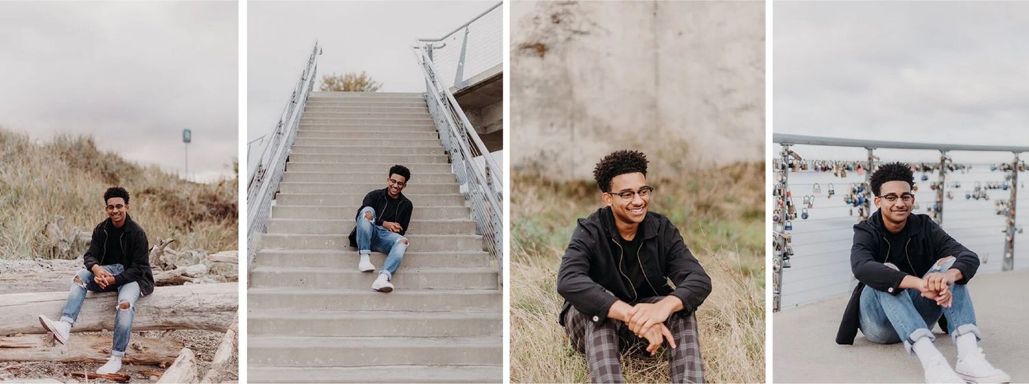 A young man with glasses, curly hair, wearing a black jacket and plaid pants, sitting outdoors on grass, smiling for senior photos.