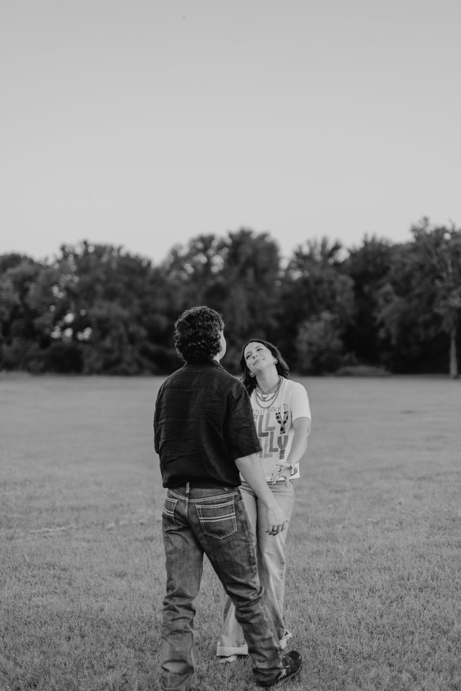 A young couple walking in a field casually together holding hands.