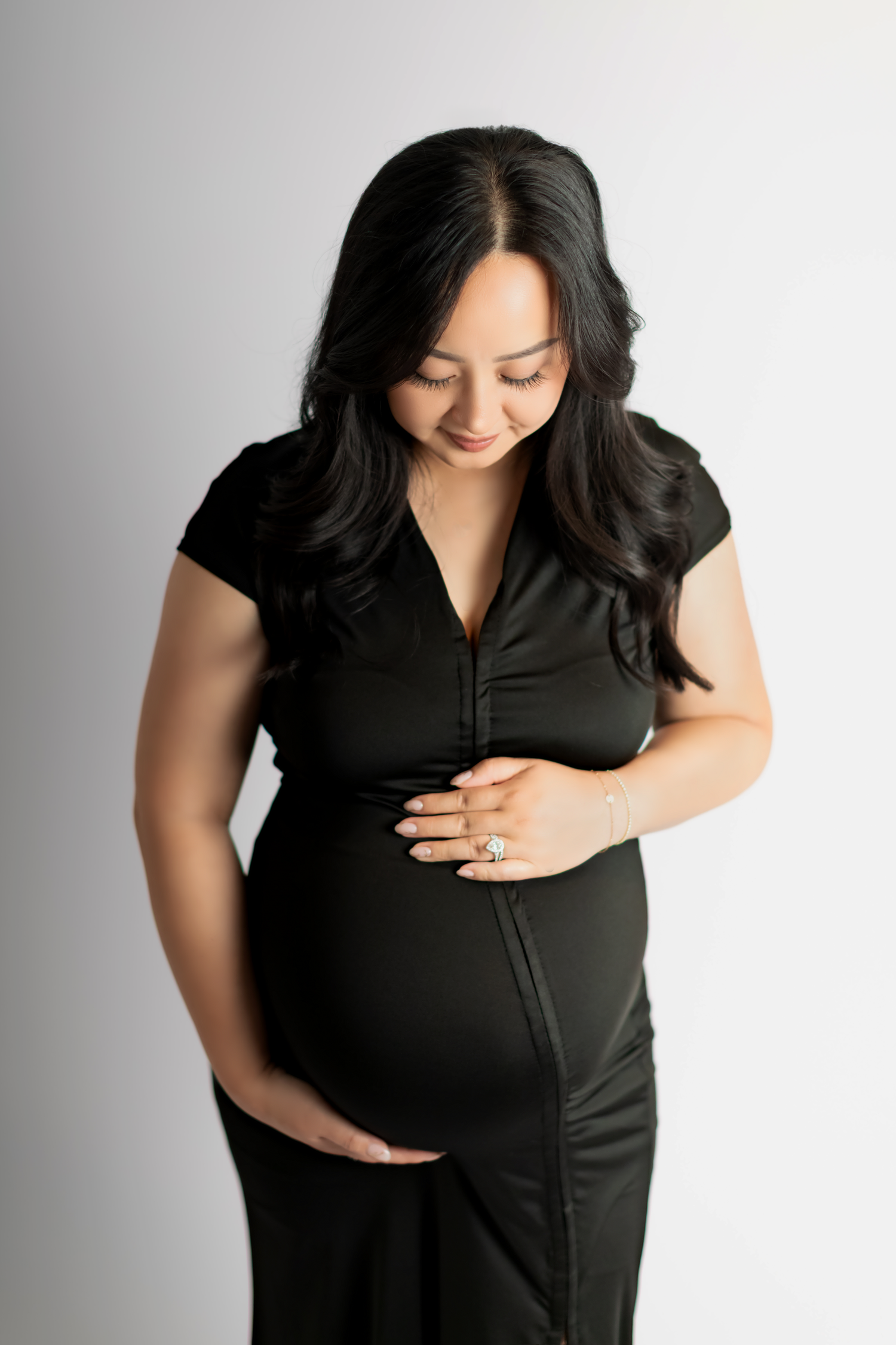 An expecting Hmong mother embracing her pregnant belly.