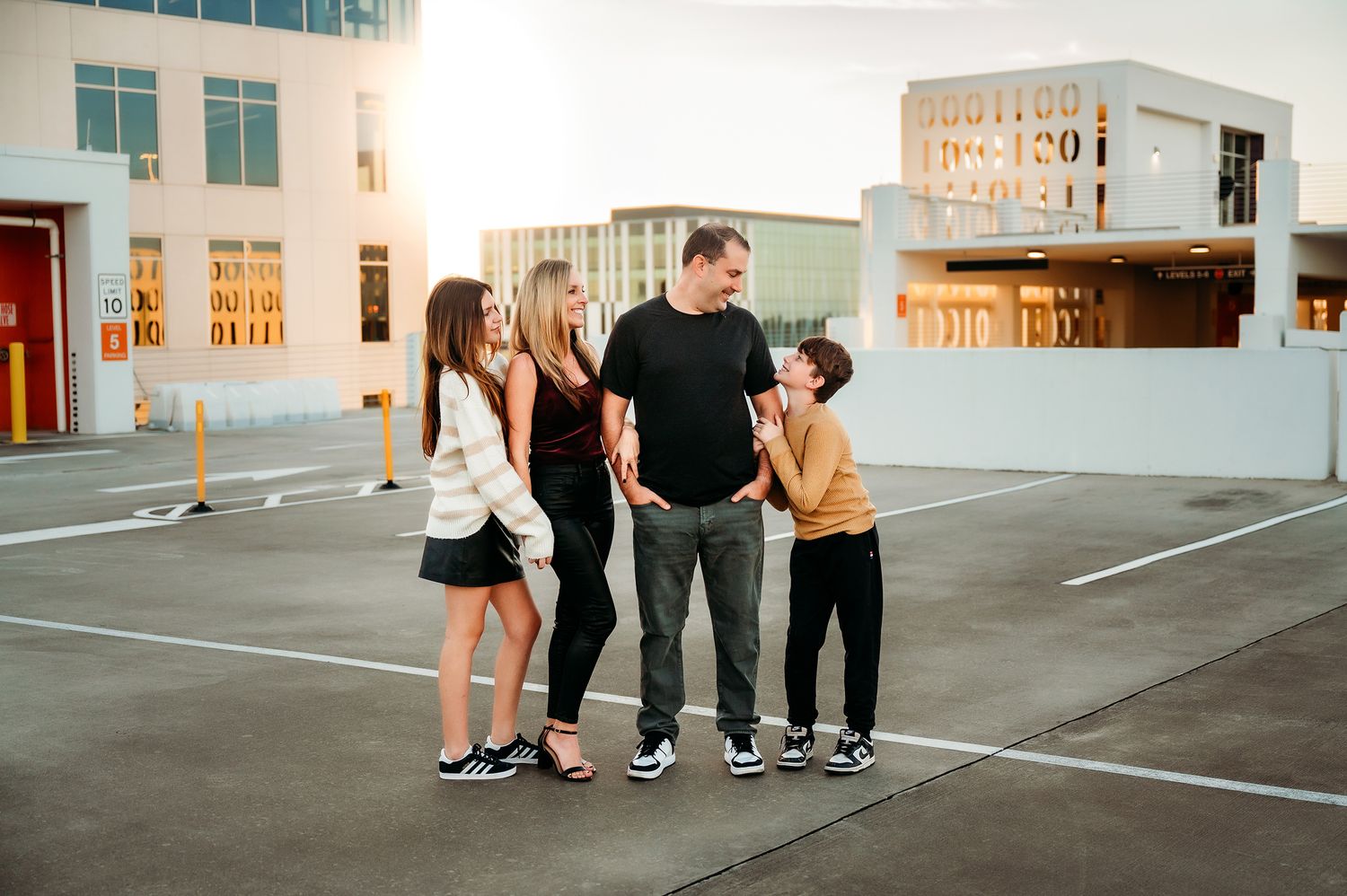 Family of four sharing a joyful moment on a rooftop parking lot bathed in warm golden sunlight.