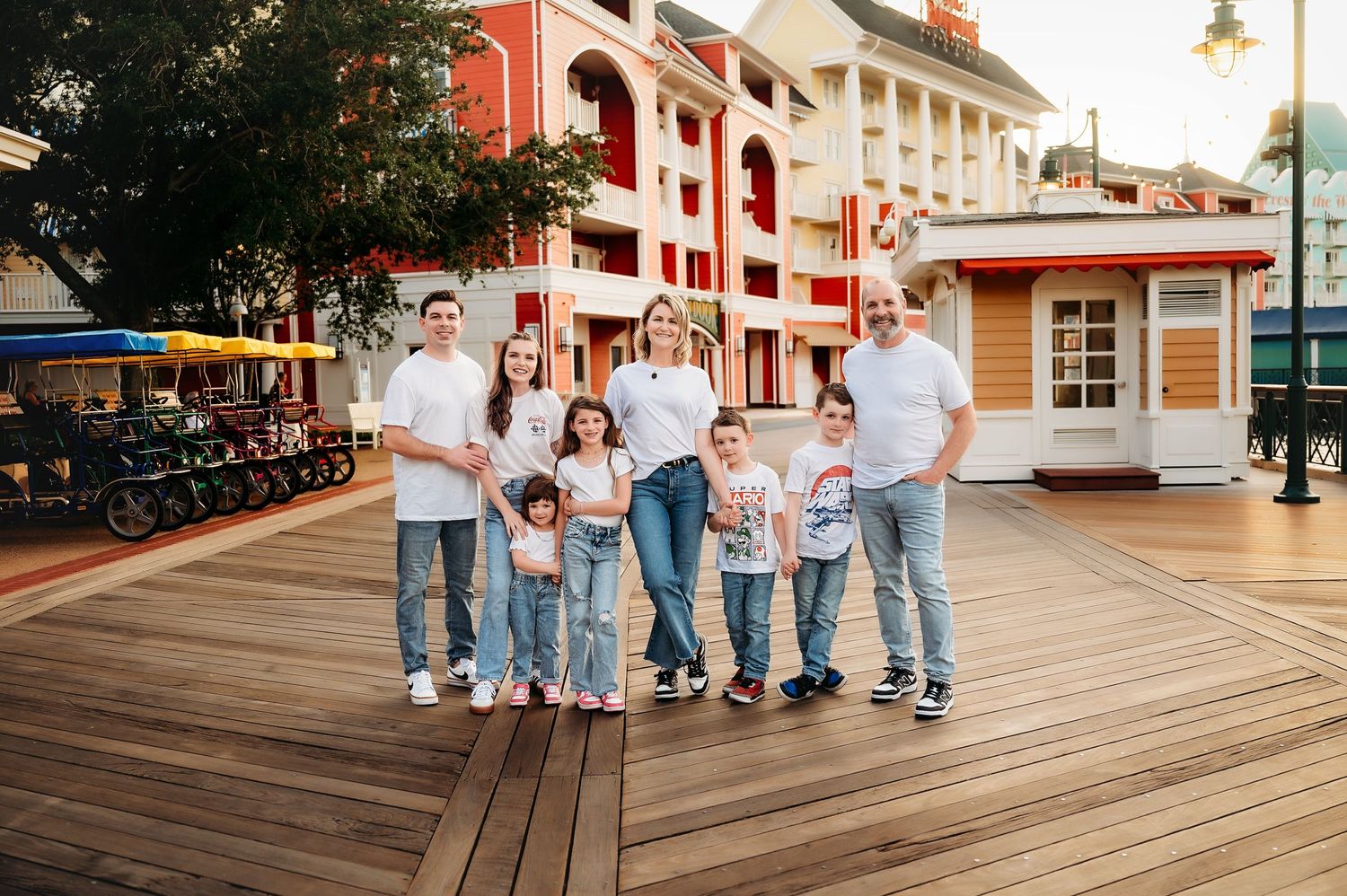Family group portrait on a wooden boardwalk in matching white outfits at a resort destination.