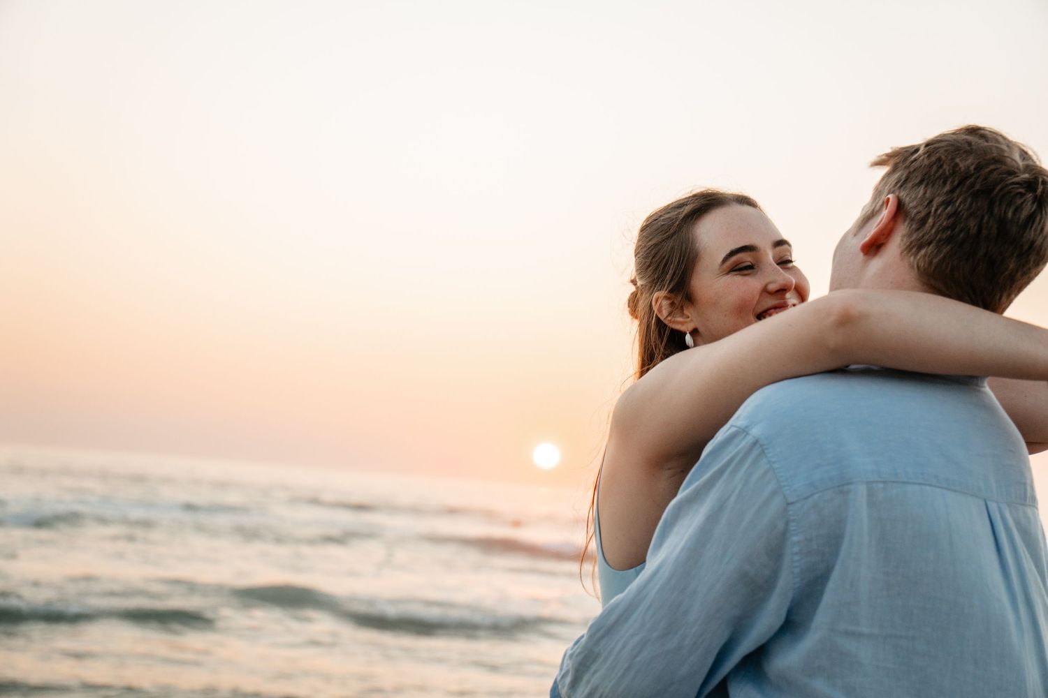 Couple embracing by the ocean at sunset during a romantic beach portrait photography session in Cape Town.